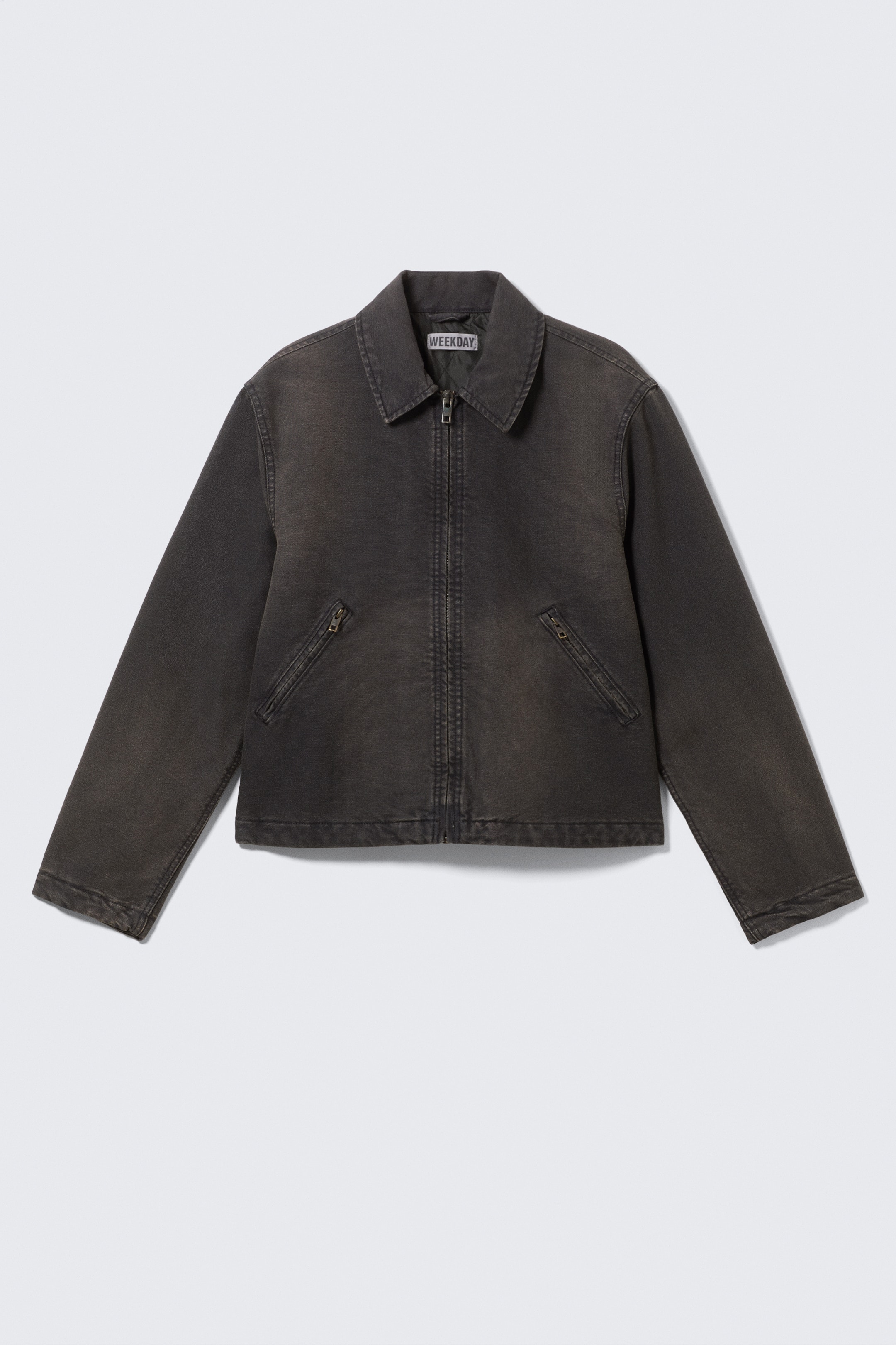 View larger image: A washed black denim jacket is presented FRONT, featuring a pointed collar, a central zip fastening, and two diagonal zippered pockets on the front.