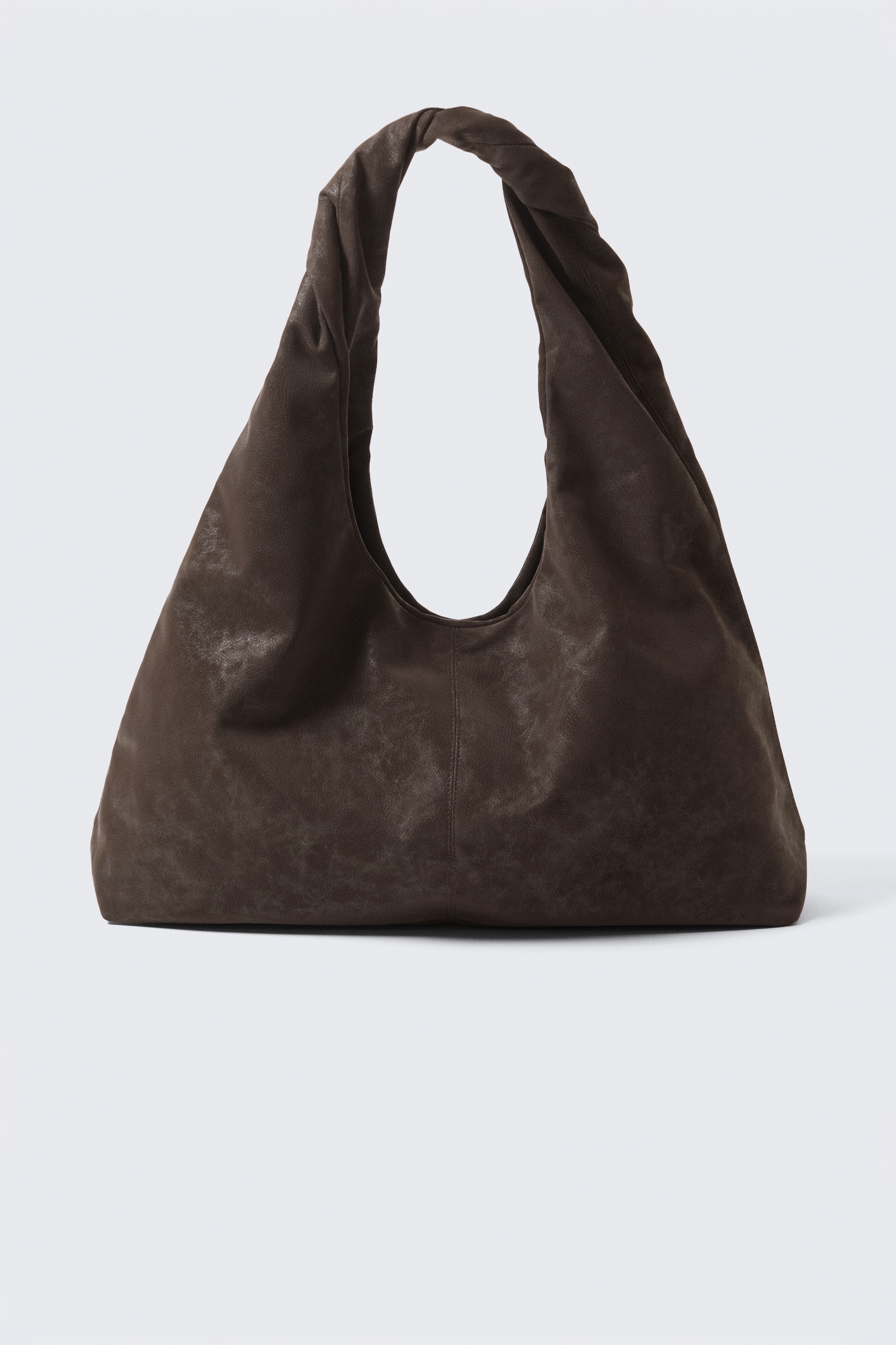 Visualizza immagine più grande: Una borsa a spalla in finta pelle marrone scuro presenta una silhouette triangolare morbida e rilassata con un volume scultoreo e un manico superiore scavato, apparendo dalla parte anteriore.