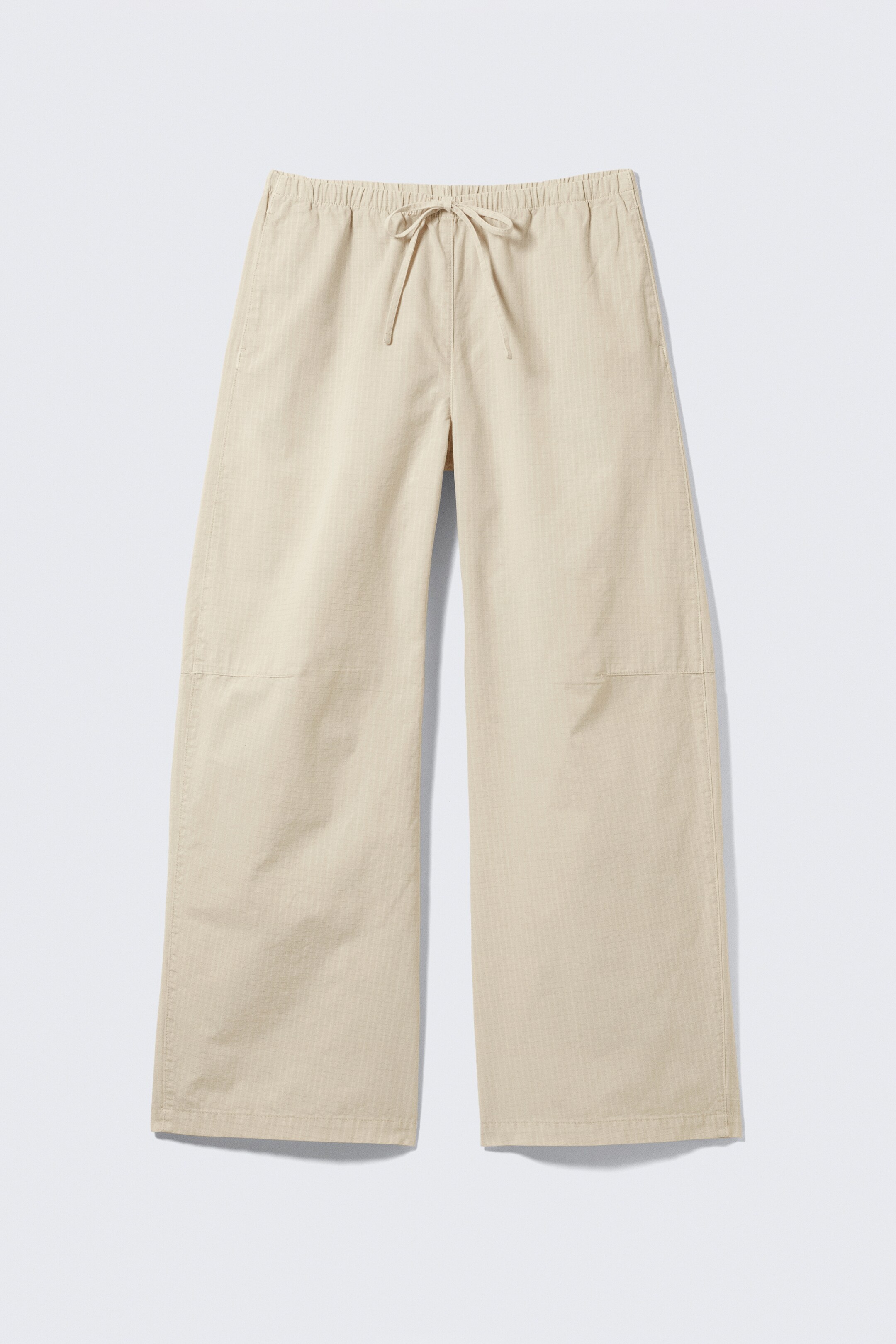Vezi imaginea mai mare: Pantalonii bej deschis cu cracul larg sunt așezați plat, cu fața în față, prezentând o talie elastică cu șnur. Cusături orizontale sunt vizibile de-a lungul coapselor superioare, iar materialul afișează o țesătură subtilă în model herringbone.