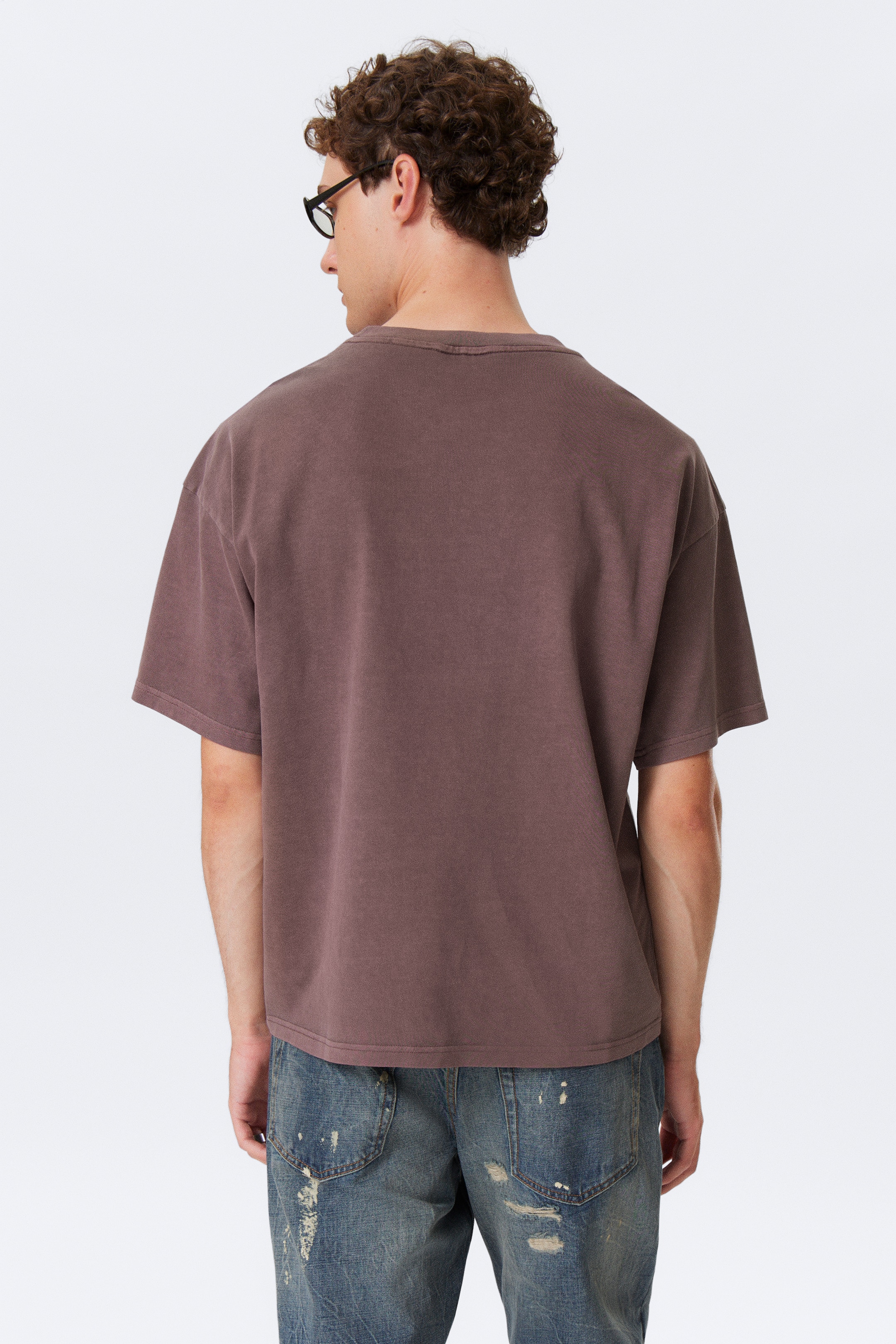 Größeres Bild anzeigen: Ein gedämpftes braunes T-Shirt wird von hinten präsentiert. Es zeichnet sich durch eine lockere Passform, einen Rundhalsausschnitt, kurze Ärmel und ein gewaschenes Finish aus.