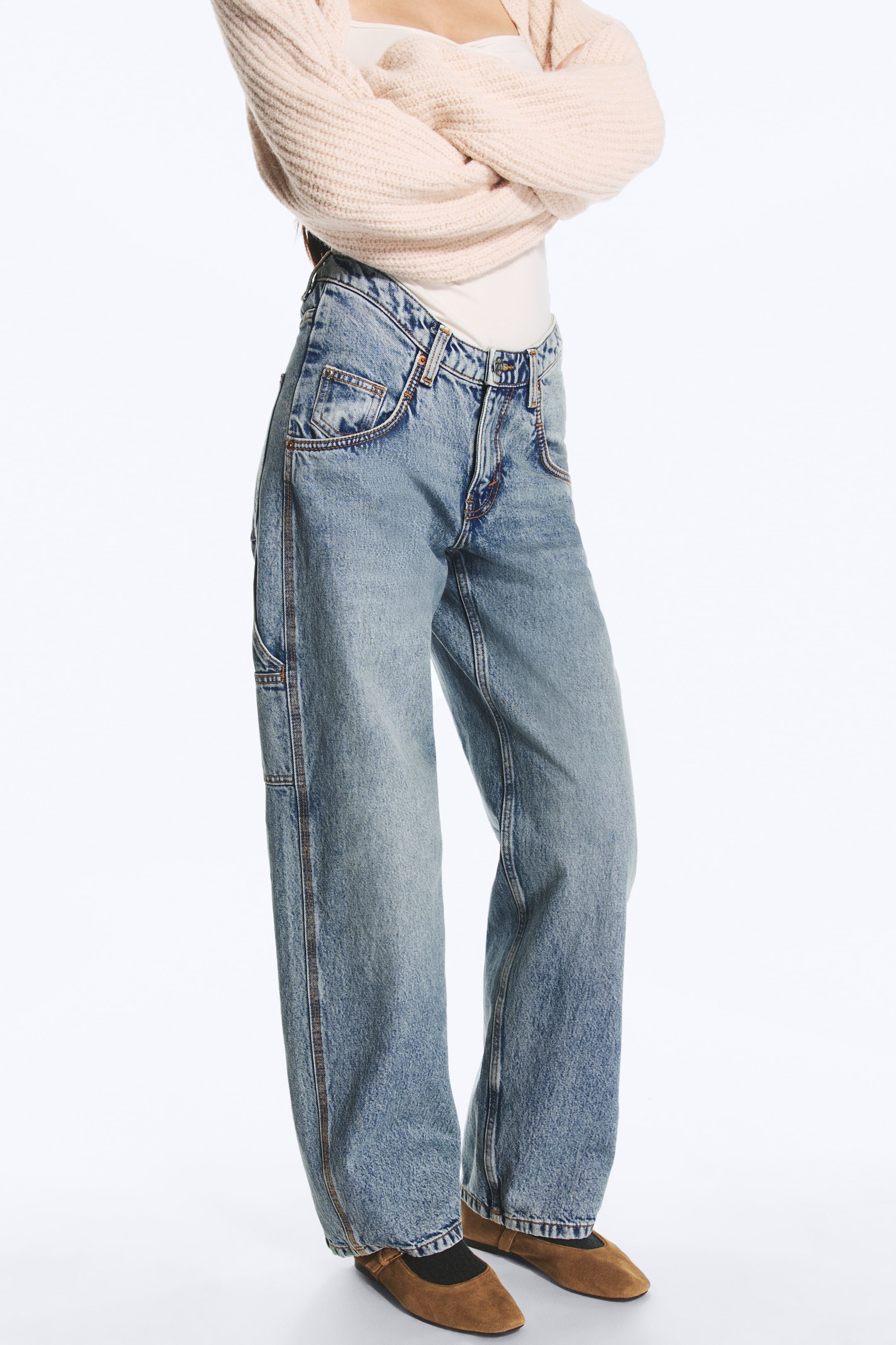 Visualizza immagine più grande: Jeans in denim blu chiaro con lavaggio chiaro, caratterizzati da una vita anteriore ribassata e da una silhouette ampia a gamba barrel, indossati dalla modella. Lo stile ispirato all'abbigliamento da lavoro presenta dettagli di cuciture utility ed è abbinato a un top color crema, un cardigan in maglia a costine rosa chiaro e scarpe basse marroni.