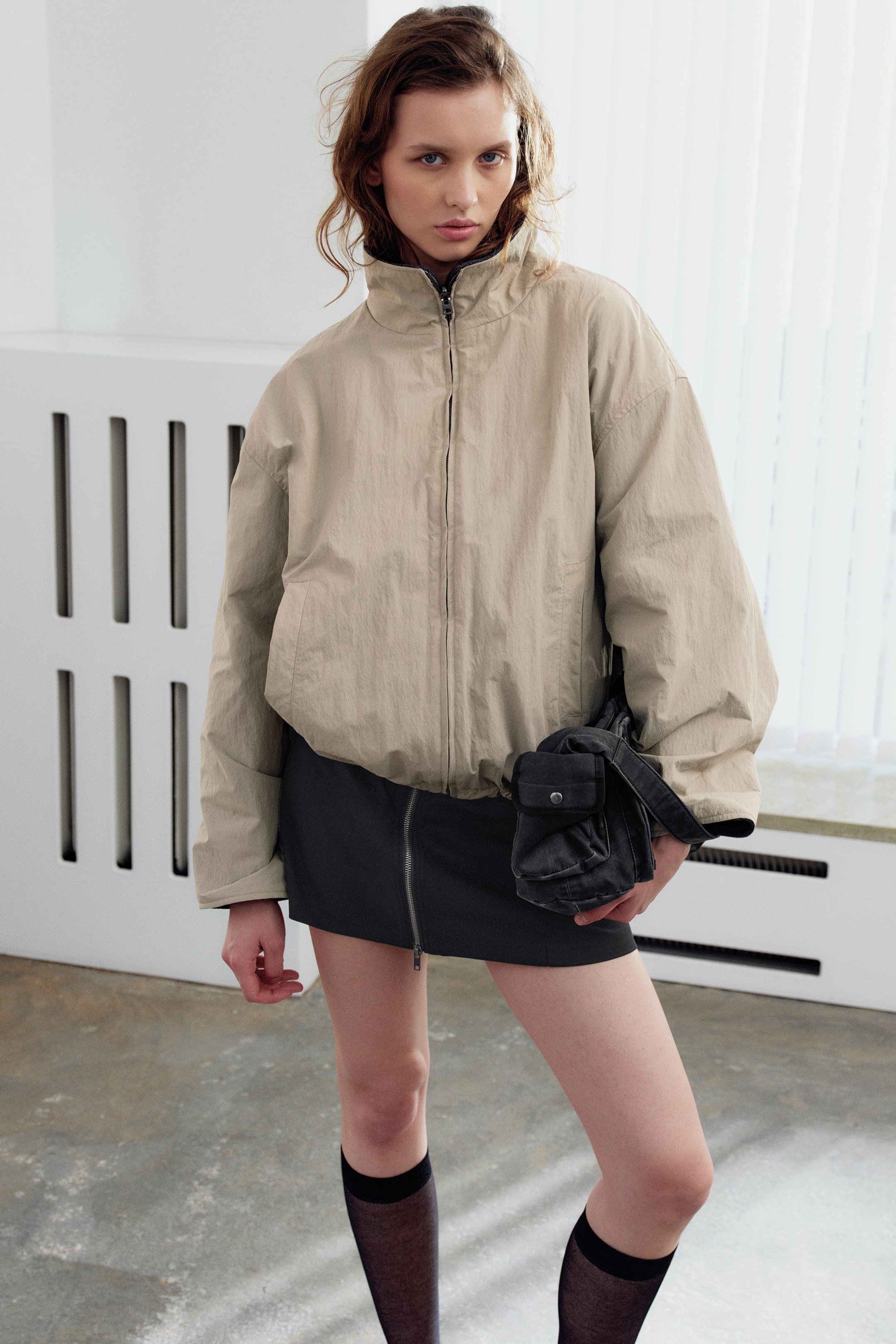 Agrandir l'image: La veste légère beige présente une texture froissée, un col montant et une fermeture zippée intégrale sur le devant. Elle affiche une coupe décontractée avec un ourlet élastiqué.