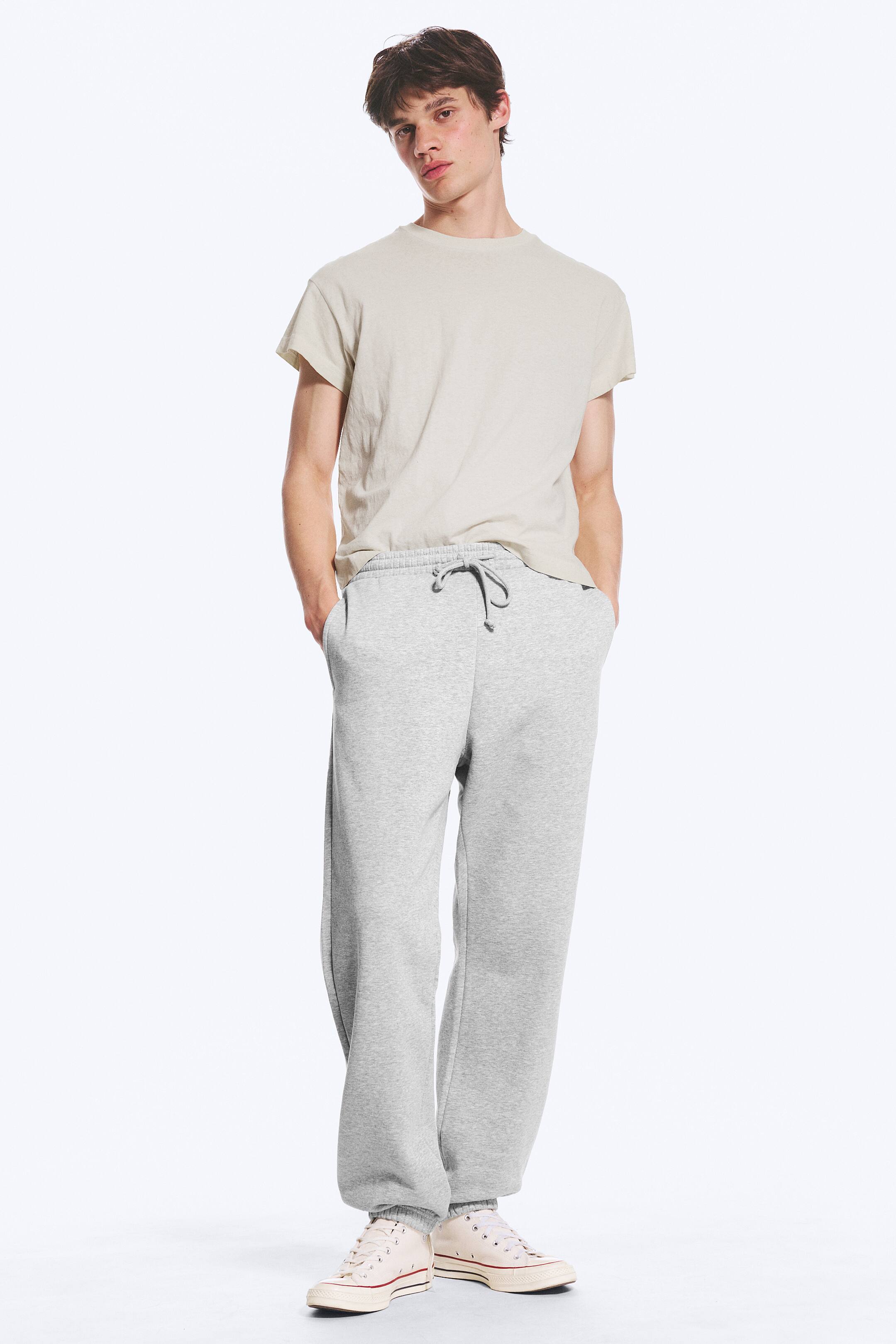 Größeres Bild anzeigen: Heather-graue Jogginghosen mit lockerem Schnitt, elastischem Bund mit sichtbarem dunkelgrauem Kordelzug, Seitentaschen und gerippten Knöchelbündchen.
