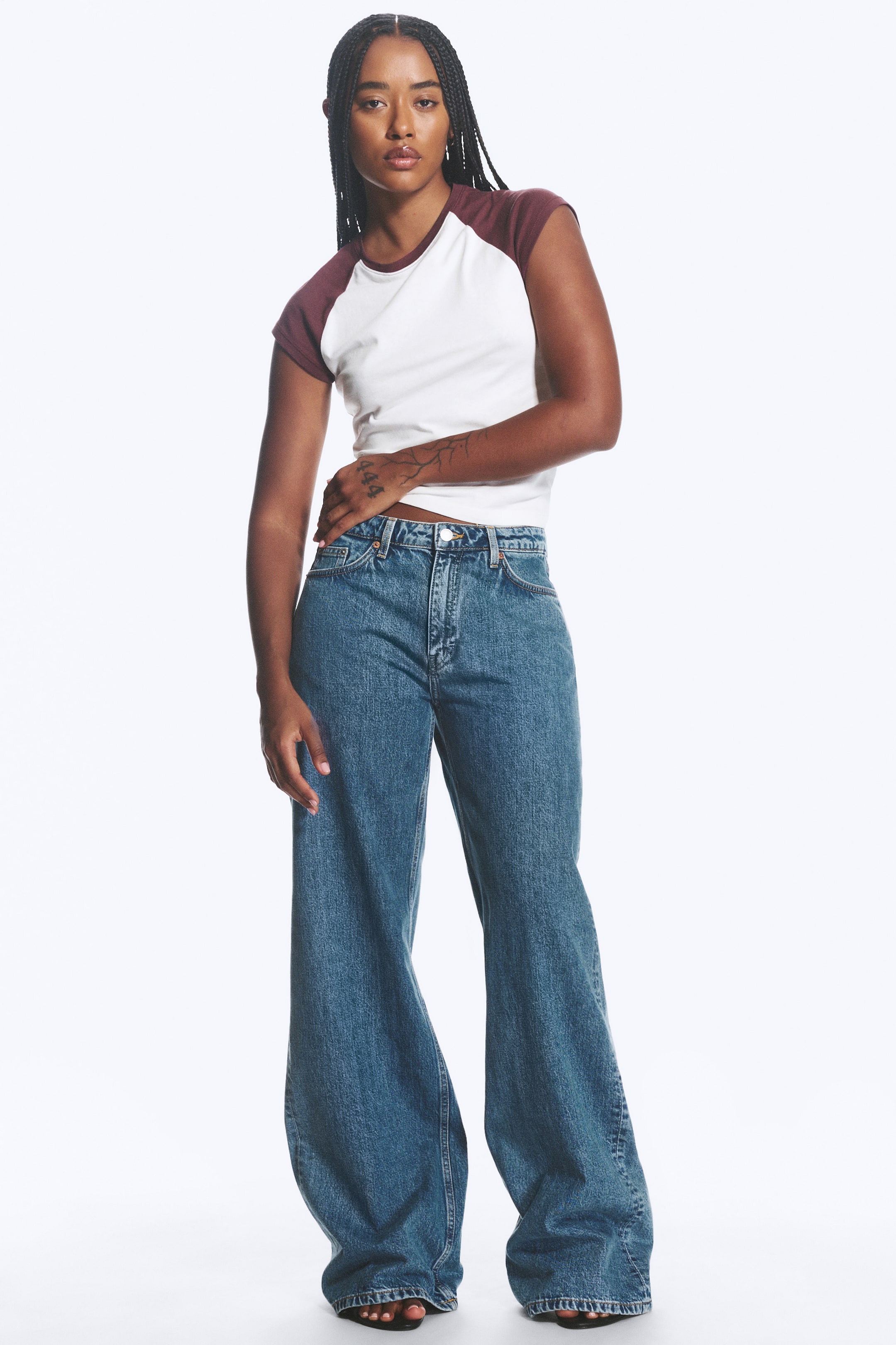 View larger image: Medium blue wash wide-leg jeans featuring a high-waisted fit with belt loops, button fastening, and visible front pockets. The full-length legs fall in a relaxed, loose fit, pooling slightly at the ankles.