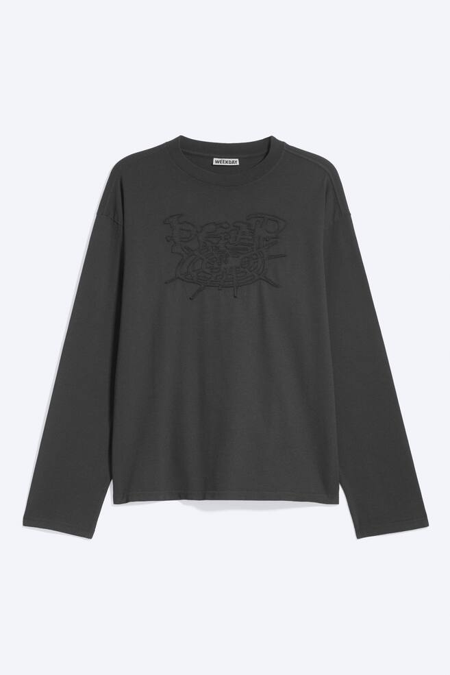 Ein dunkelgraues, kastig geschnittenes Langarm-T-Shirt wird in der Frontansicht gezeigt und verfÃ¼gt Ã¼ber einen gerippten Rundhalsausschnitt, Ã¼berschnittene Schultern und eine tonale, gestickte Grafik mittig auf der Brust. - 1