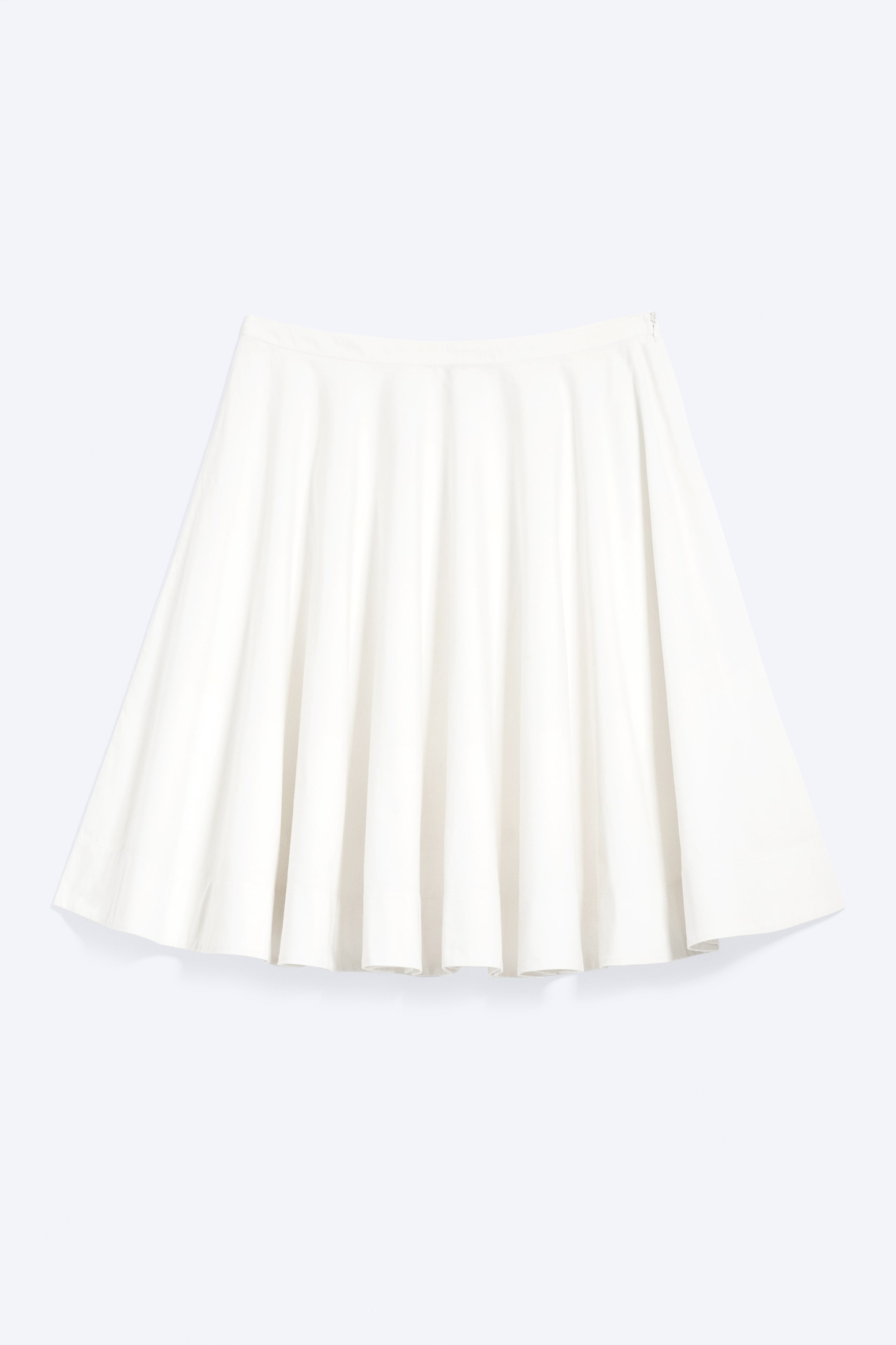 Agrandir l'image: Une jupe patineuse crème présente une ceinture lisse et des plis doux et fluides, créant une silhouette évasée. Une fermeture éclair subtile est visible sur le côté droit.