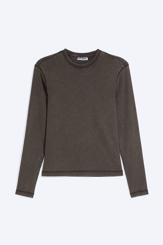 Un T-shirt Ã  manches longues en coton cÃ´telÃ© marron foncÃ© dÃ©lavÃ© est posÃ© Ã  plat, face avant visible, mettant en valeur son col rond, sa coupe slim et ses surpiqÃ»res flatlock le long des emmanchures, des poignets et de lâourlet. - 1