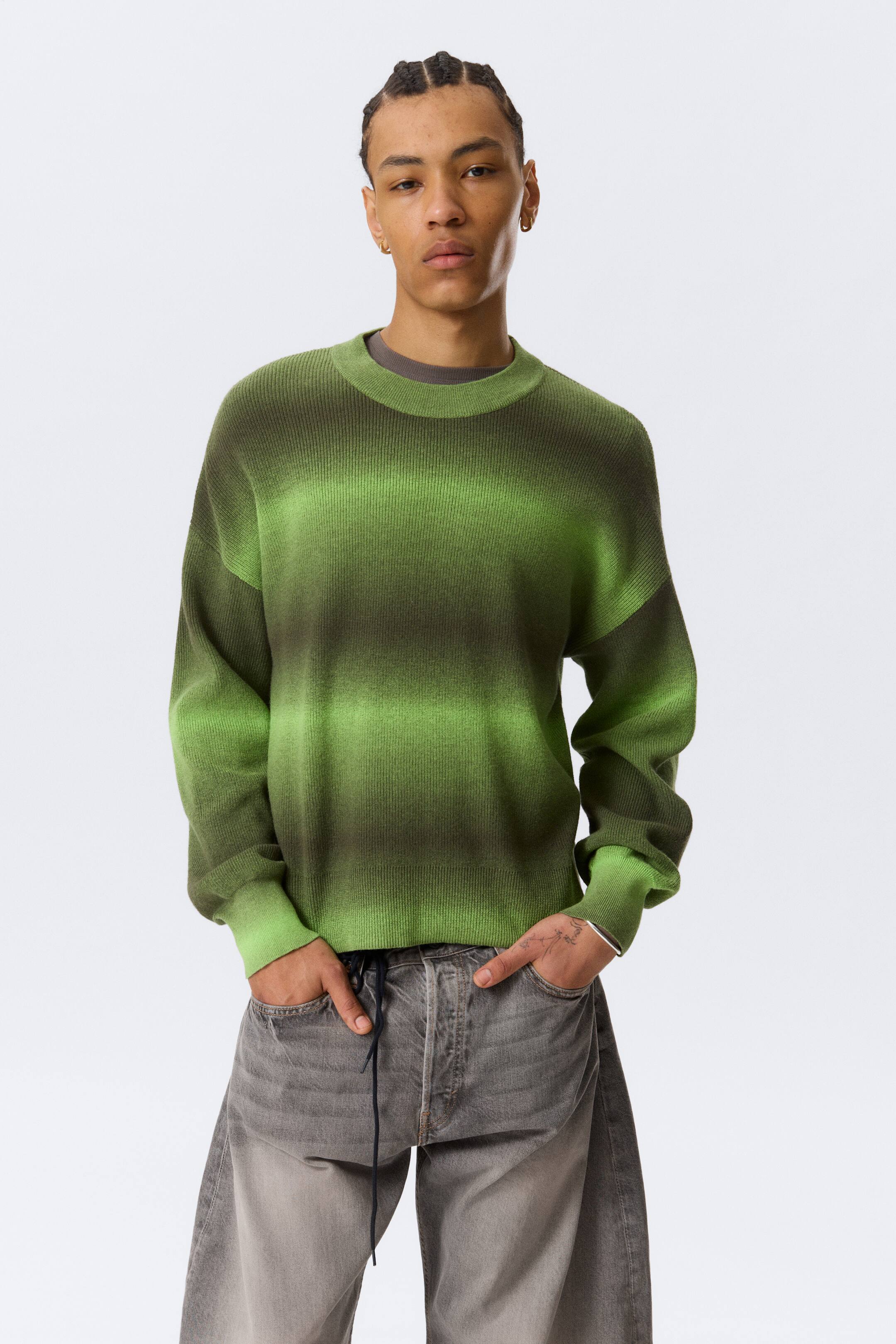 Grösseres Bild ansehen: Ein nach vorne gerichteter Strickpullover präsentiert ein horizontales Ombré-Muster mit abwechselnden Streifen aus Dunkelgrün und leuchtendem Limettengrün, ausgestattet mit einem gerippten Rundhalsausschnitt, gerippten Bündchen und einem gerippten Saum. Unter dem Ausschnitt ist ein dunkles T-Shirt geschichtet.