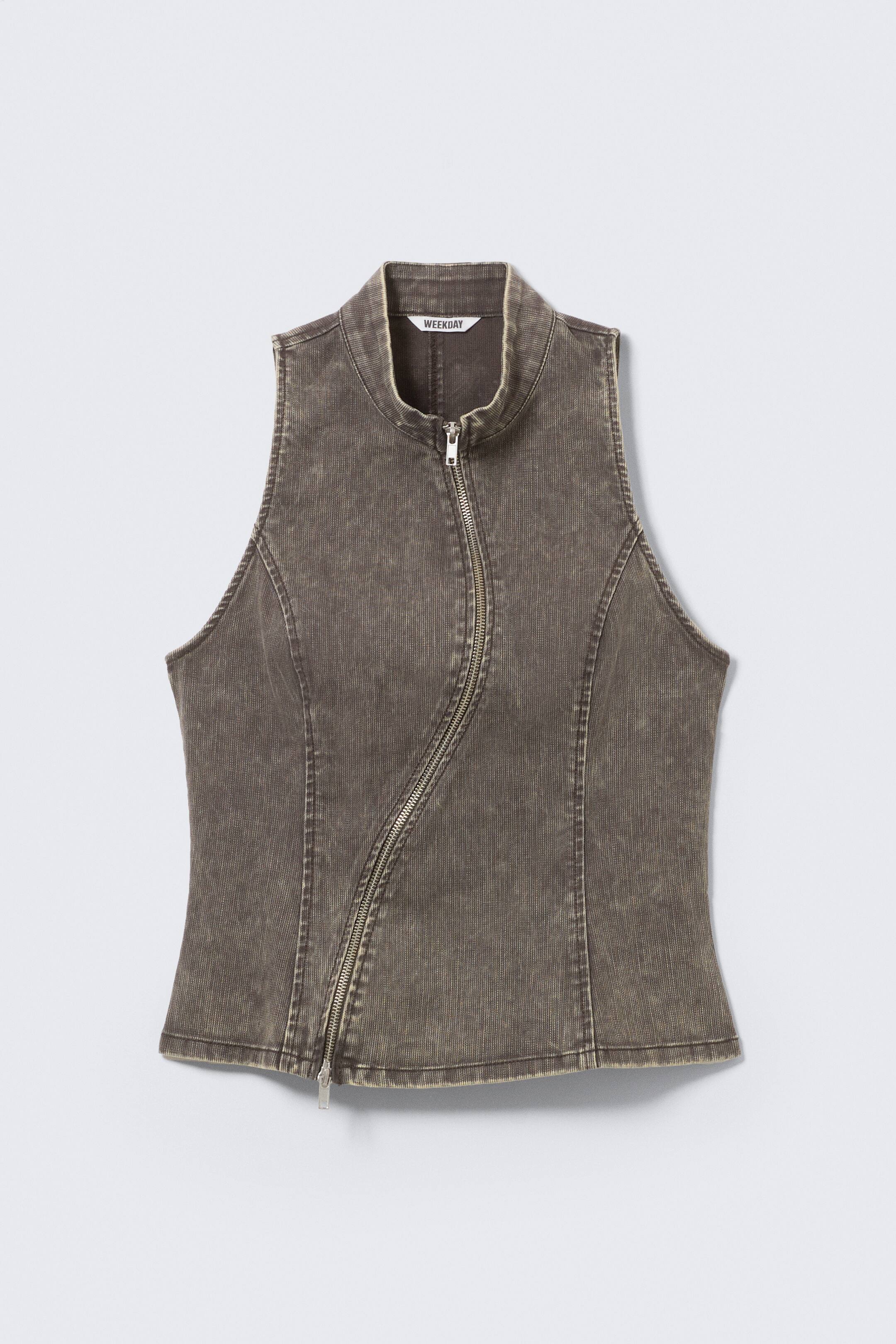 View larger image: A faded dark grey sleeveless vest is showcased at the FRONT, featuring a stand-up collar and a prominent vertical ribbed texture. It is designed with a full-length, silver-toned, asymmetrical zip fastening running from the bottom left to the top right, with vertical seams creating a fitted silhouette.