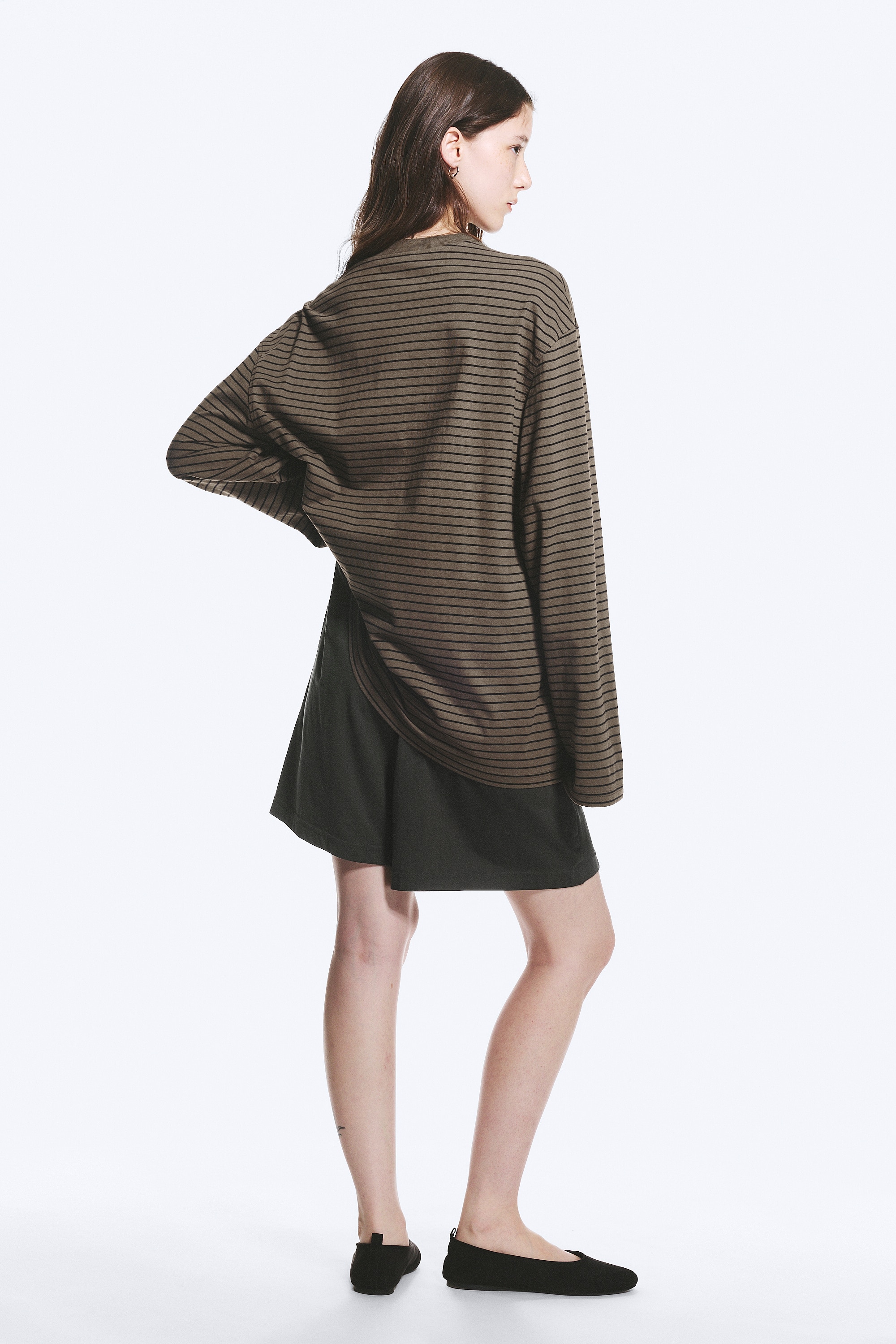 Camiseta de manga larga y corte extragrande en verde oliva con finas rayas horizontales negras, vista de frente, con una etiqueta blanca 'WEEKDAY' en el cuello redondo acanalado, mangas extra largas y espaciosas, y dobladillos doblados.