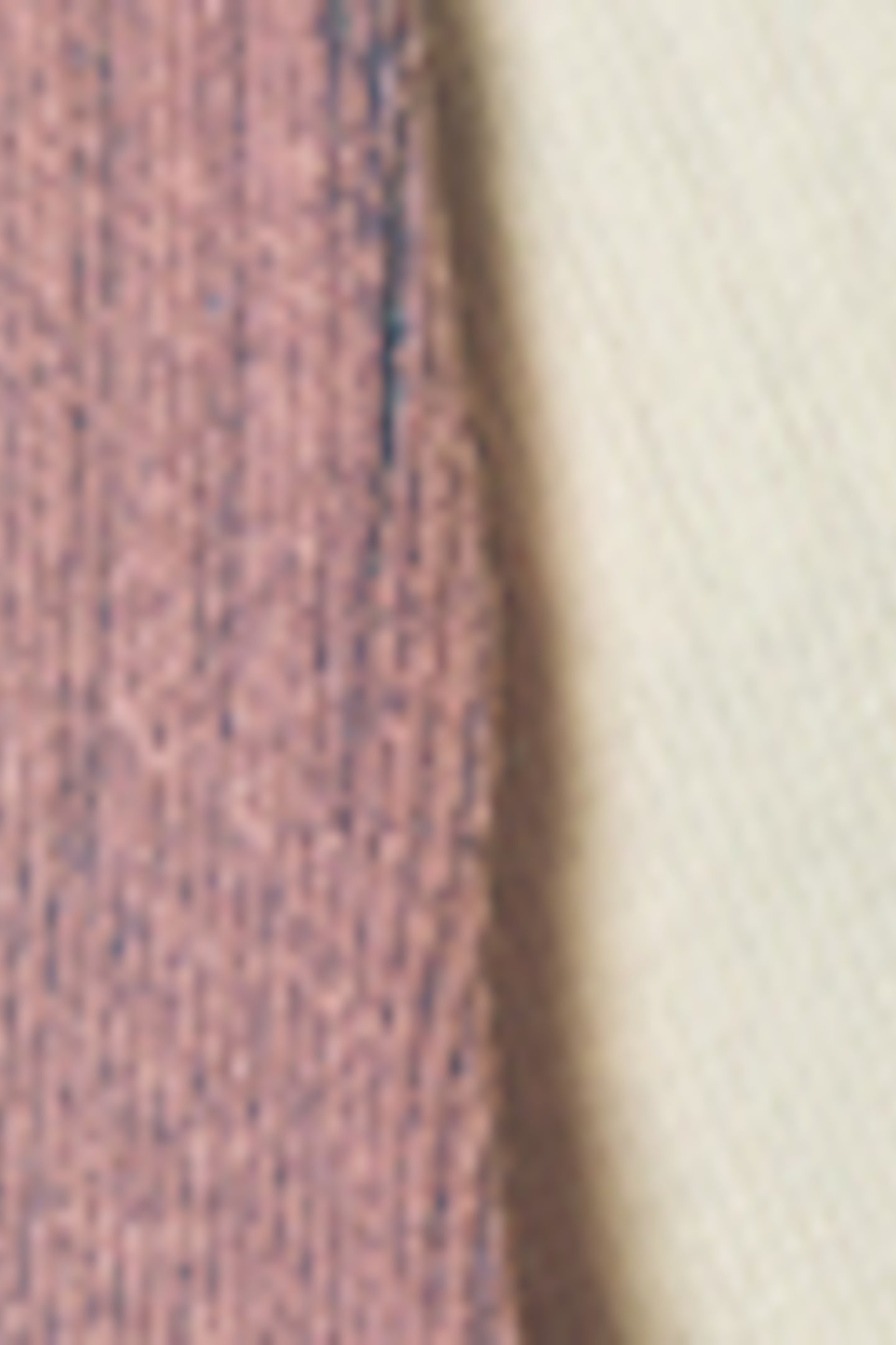 Προβολή μεγαλύτερης εικόνας: Ένα ροζ, υφασμάτινο ύφασμα με υφή είναι τοποθετημένο δίπλα σε ένα υφασμάτινο ύφασμα σε κρεμ χρώμα. Το ροζ ύφασμα παρουσιάζει μια ελαφρώς φθαρμένη άκρη εκεί όπου συναντά το κρεμ ύφασμα.