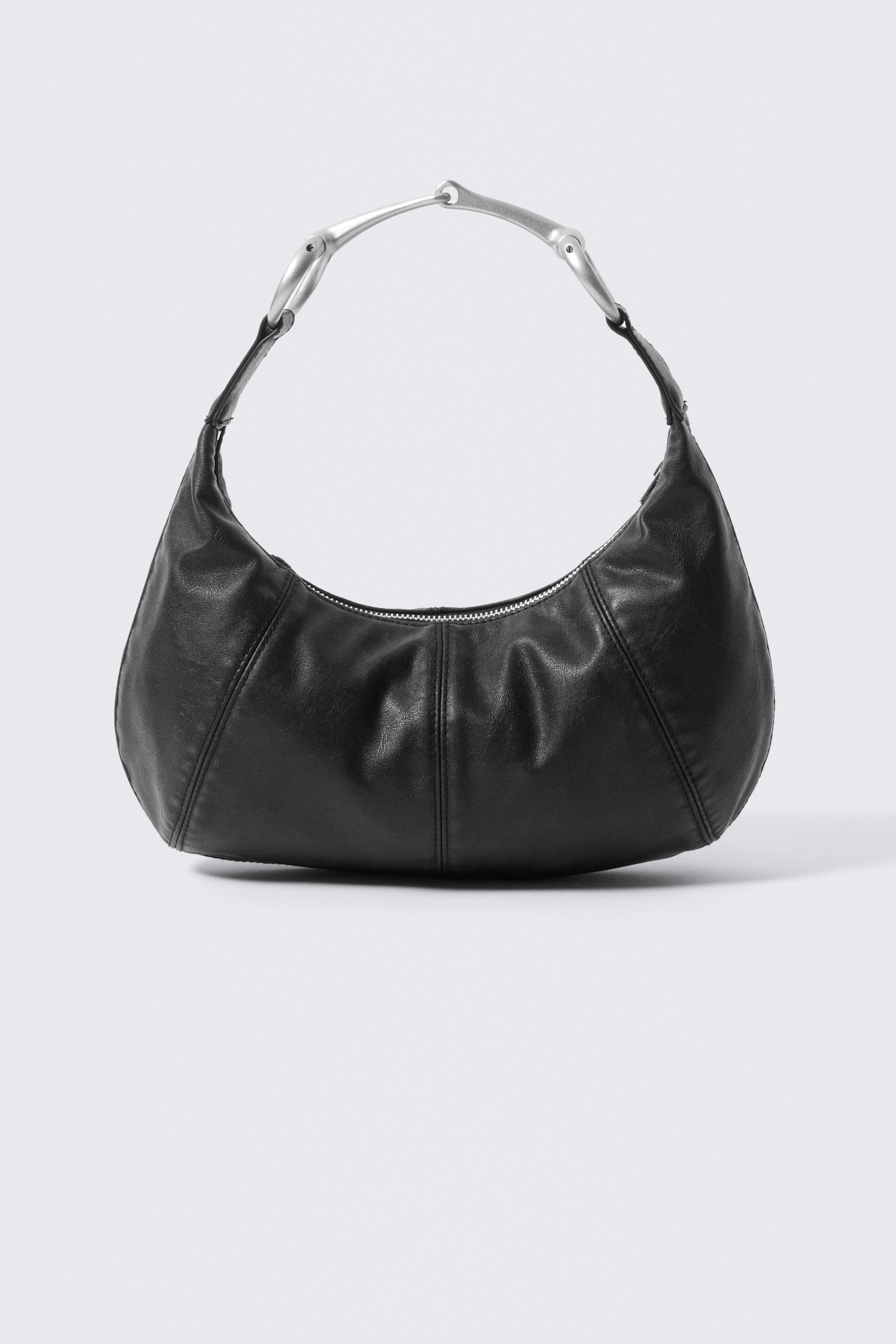 Grösseres Bild ansehen: Eine schwarze Lederhalbmondtasche ist nach vorne gerichtet und verfügt über einen silberfarbenen Metallgriff mit zwei gebogenen Segmenten, die durch ein zentrales Glied verbunden sind. Ein silberner Reißverschluss verläuft entlang der oberen Öffnung, und ihr Körper zeigt vertikale Nähte.