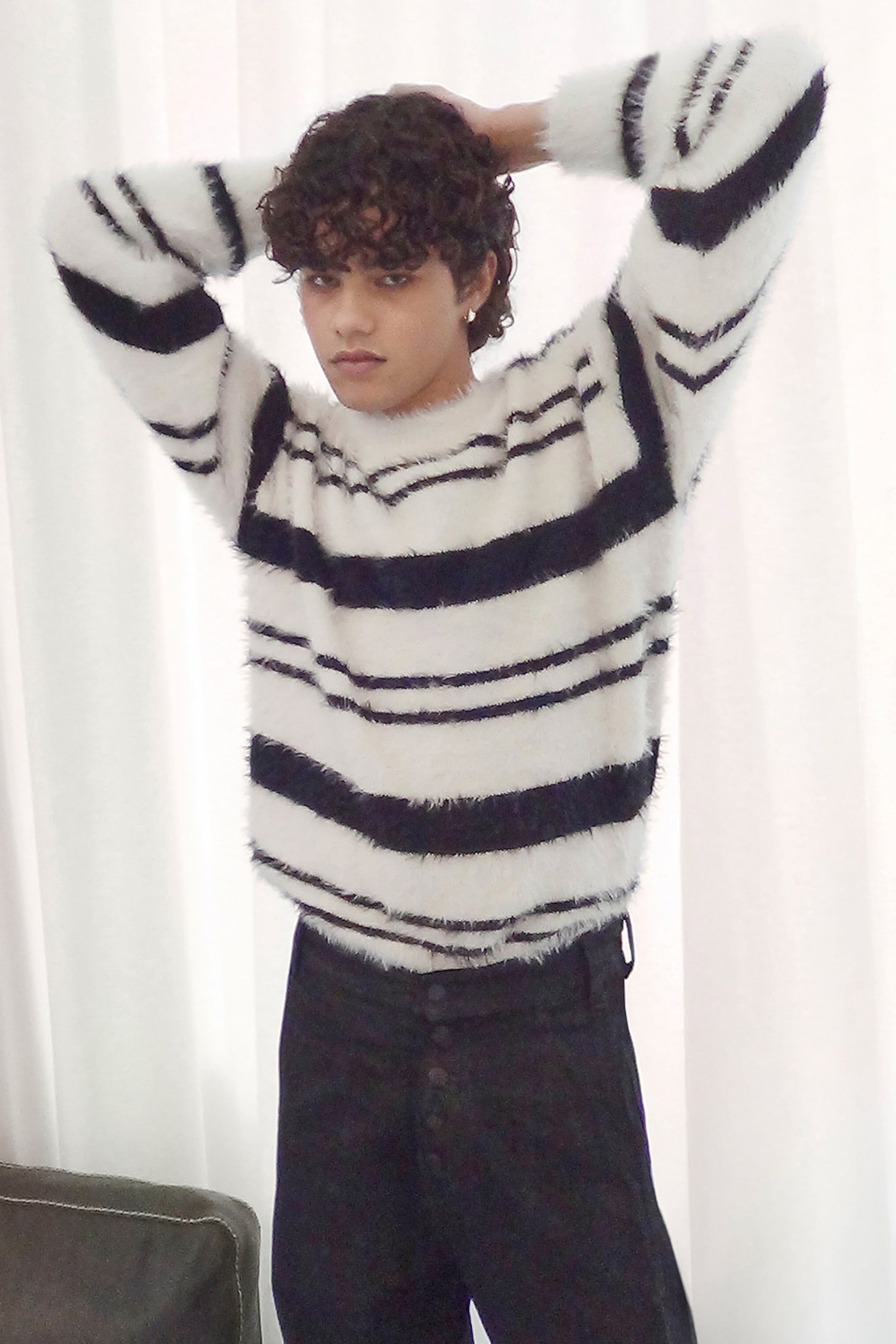 Model wearing a black & white striped knitted sweater paired with a pair of black trousers
