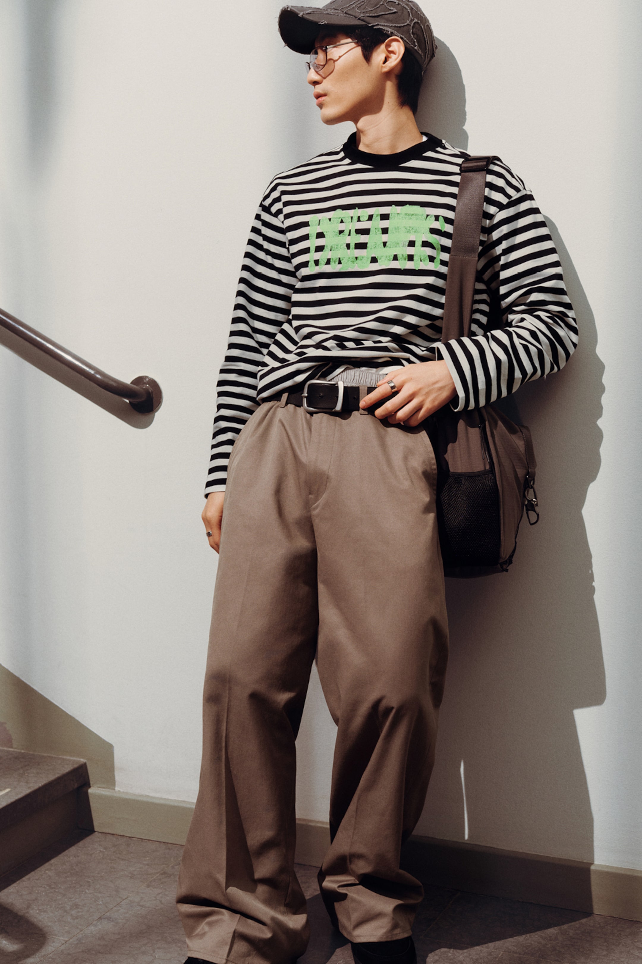Model wearing a pair of Brown trousers paired with a graphic striped longsleeve t-shirt