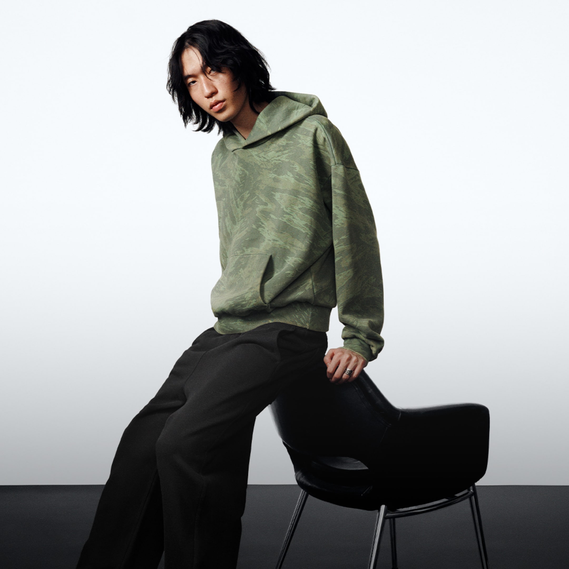 Model wearing a pair of black Sammy scuba sweatpants and a green graphic hoodie