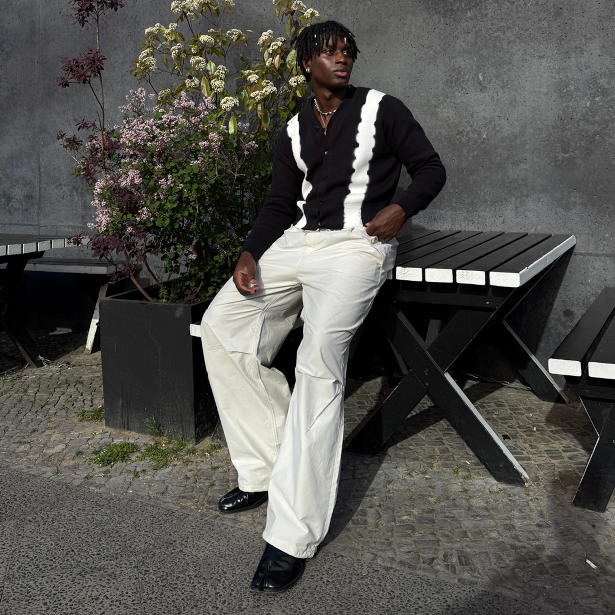 Model wearing a pair of white parachute trousers paired with a black & white printed cardigan