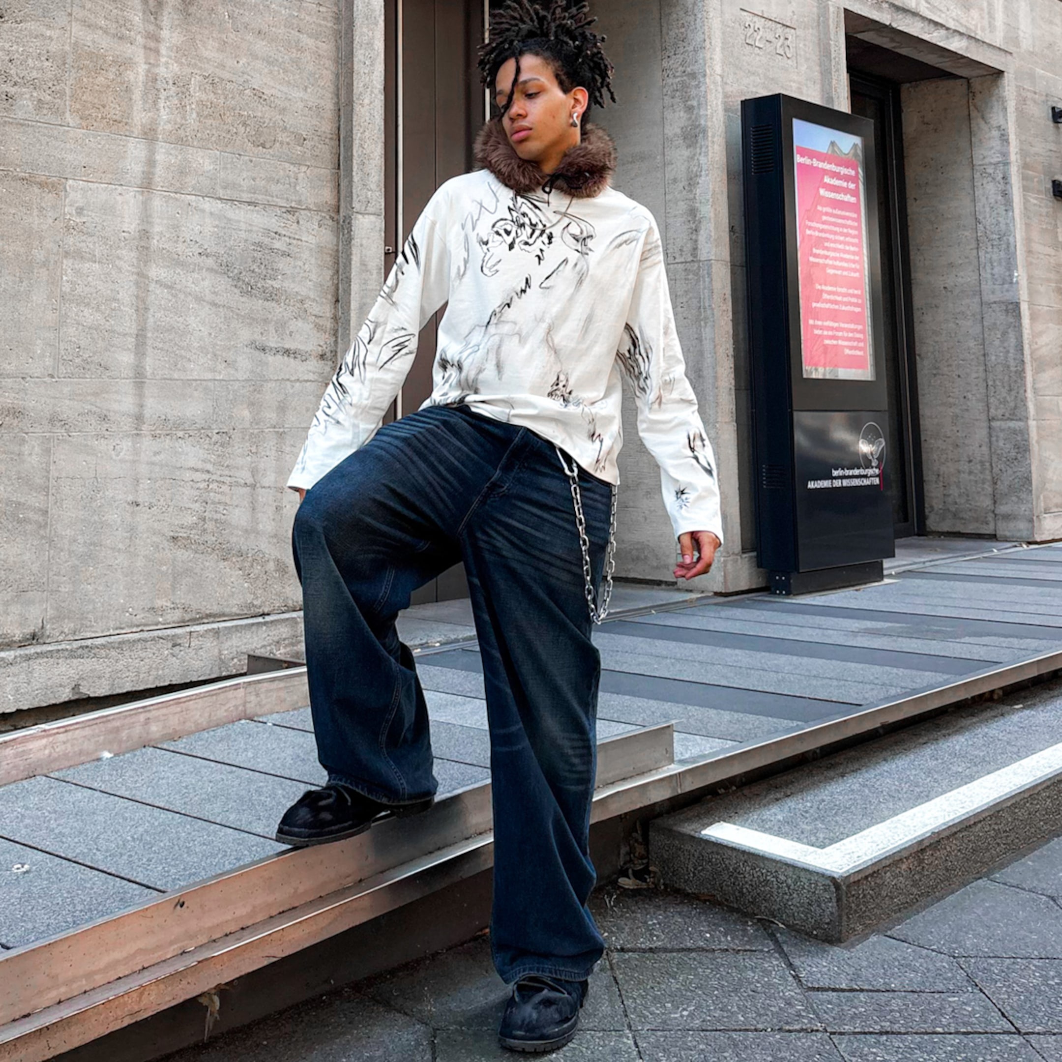 Model wearing a pair of blue loose fit jeans with a graphic long sleeve t-shirt