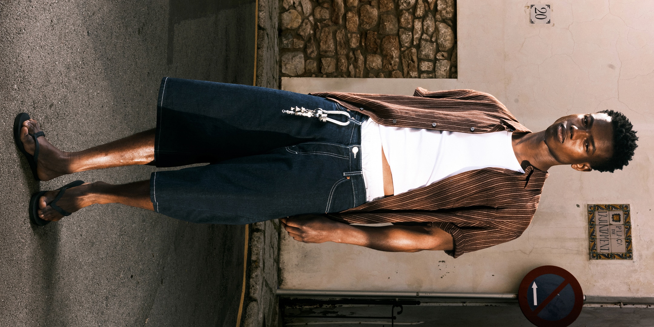 Model wearing a pair of astro loose shorts paired with a brown striped shirt