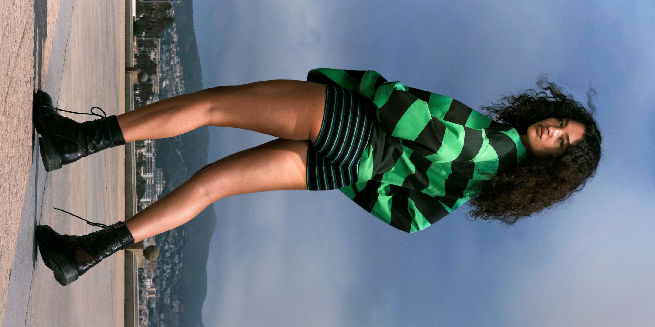 Model wearing a pair of green and black striped hotpants together with a long sleeve top in green and black