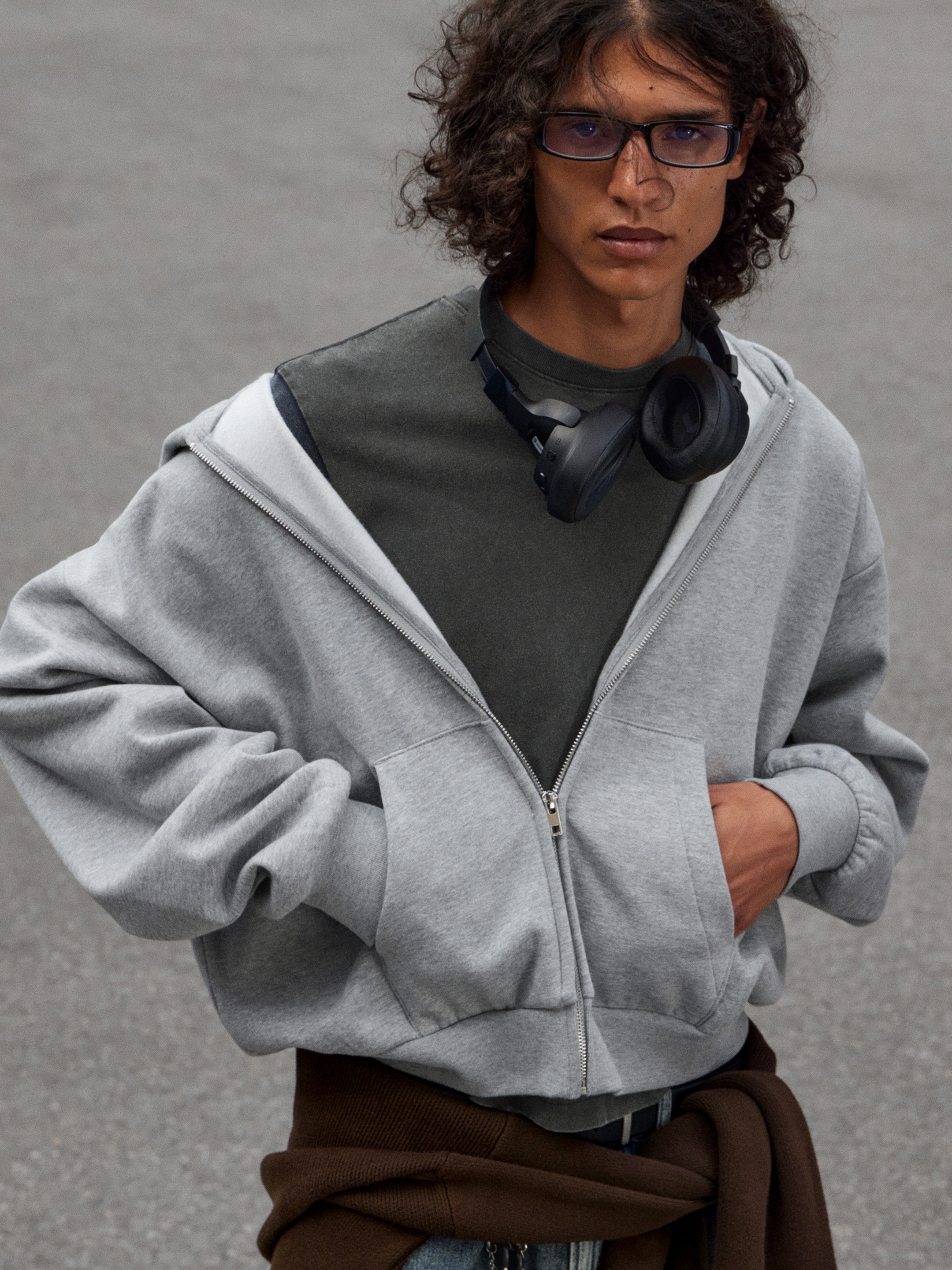 Model wearing a grey zip hoodie over a dark grey t-shirt