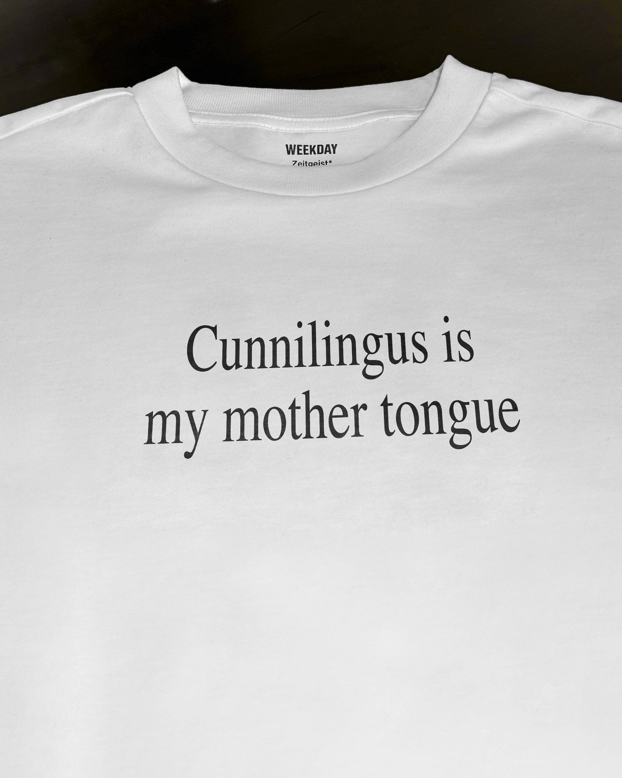 A person wearing a printed white Zeitgeist t-shirt saying “Sorry I missed your call. I was watching it ring till it stopped.”