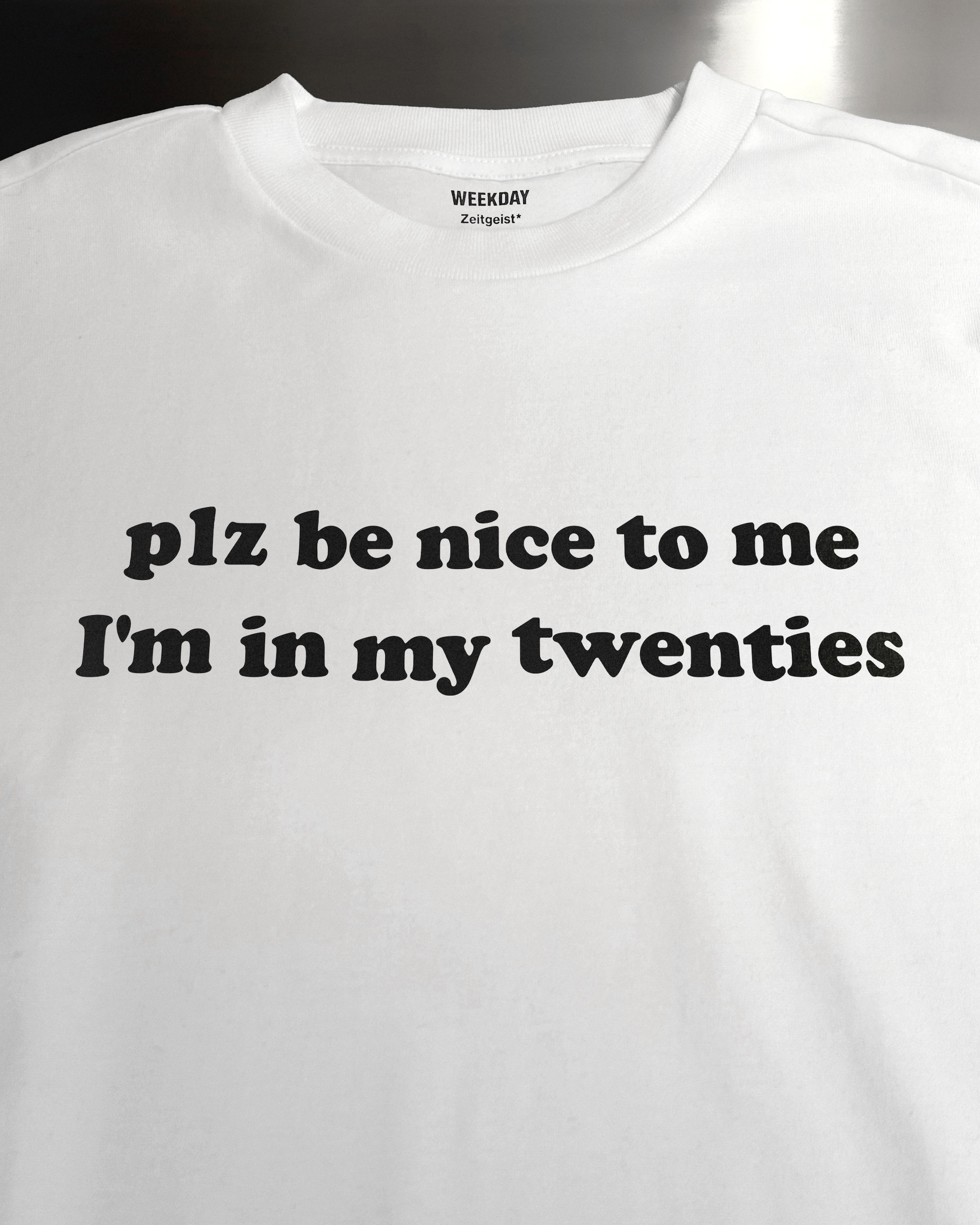 A person wearing a printed white Zeitgeist t-shirt saying “Sorry I missed your call. I was watching it ring till it stopped.”