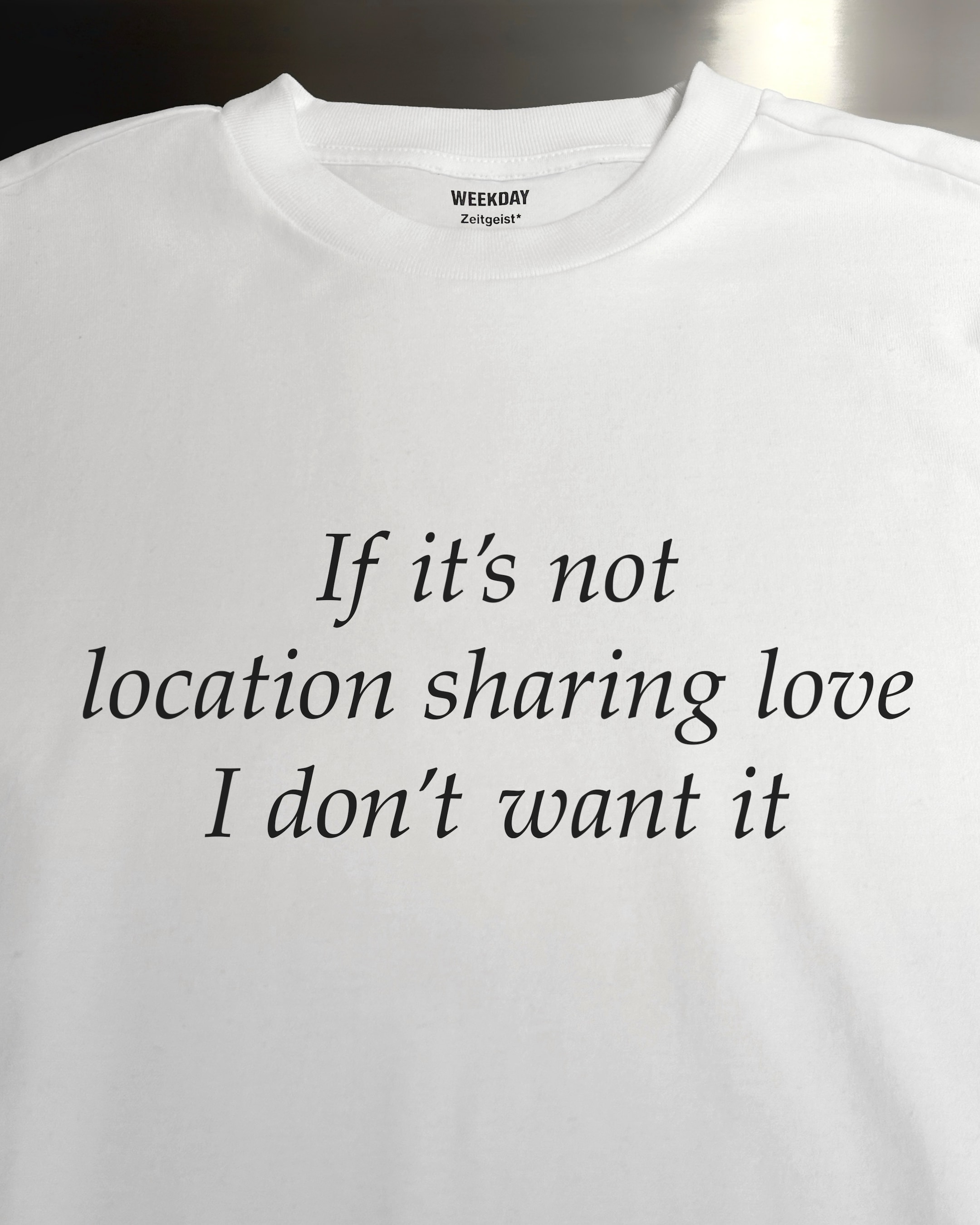 A person wearing a printed white Zeitgeist t-shirt saying “Sorry I missed your call. I was watching it ring till it stopped.”