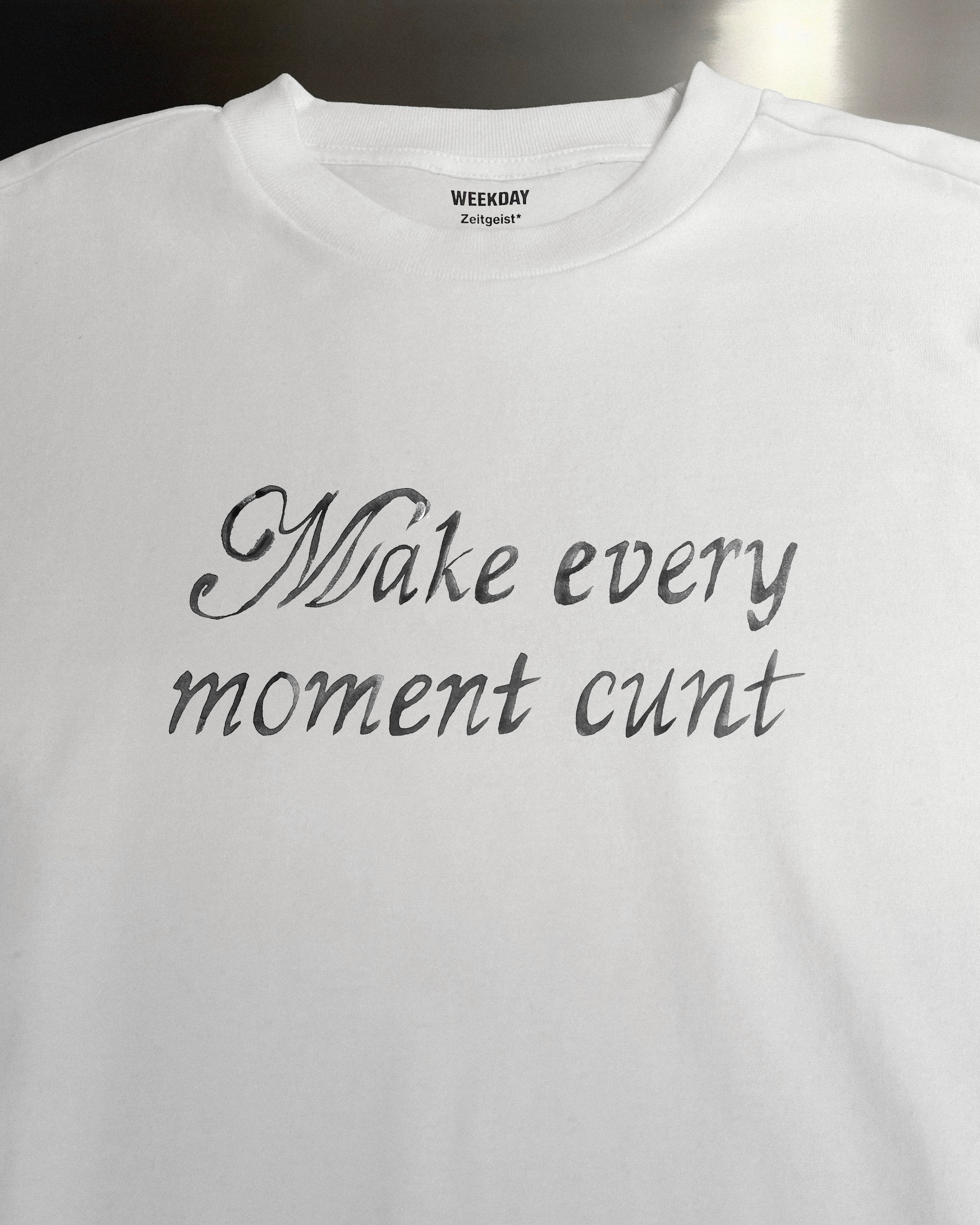 A person wearing a printed white Zeitgeist t-shirt saying “Sorry I missed your call. I was watching it ring till it stopped.”