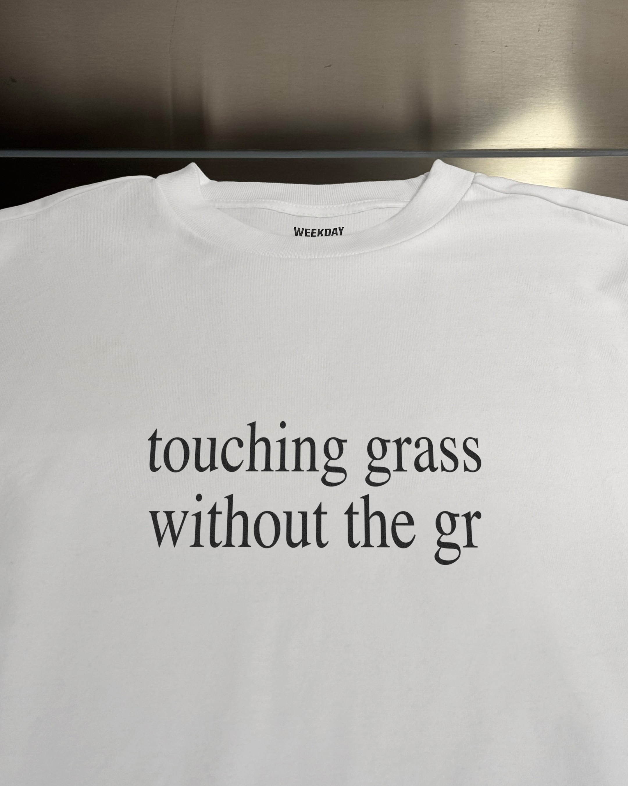 A person wearing a printed white Zeitgeist t-shirt saying “Sorry I missed your call. I was watching it ring till it stopped.”