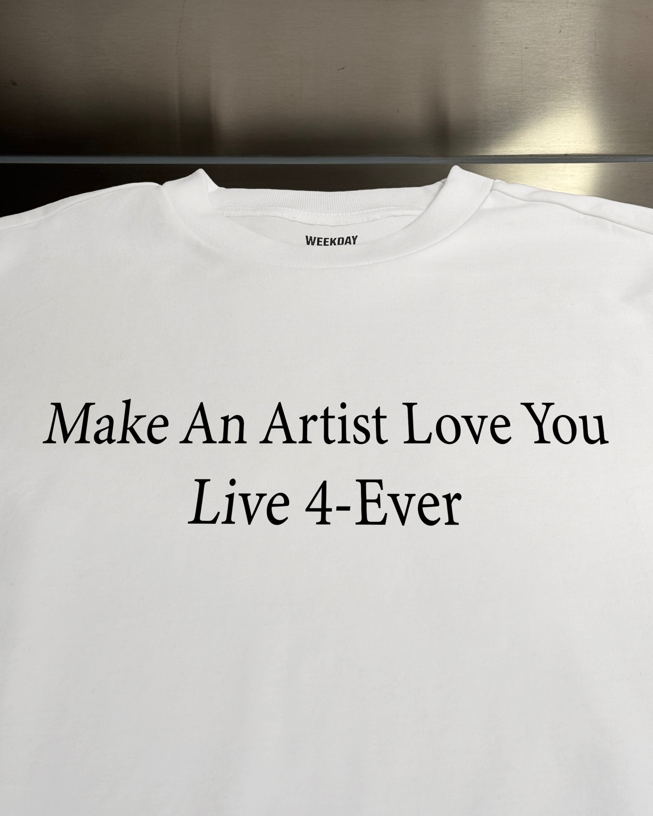 A person wearing a printed white Zeitgeist t-shirt saying “Sorry I missed your call. I was watching it ring till it stopped.”