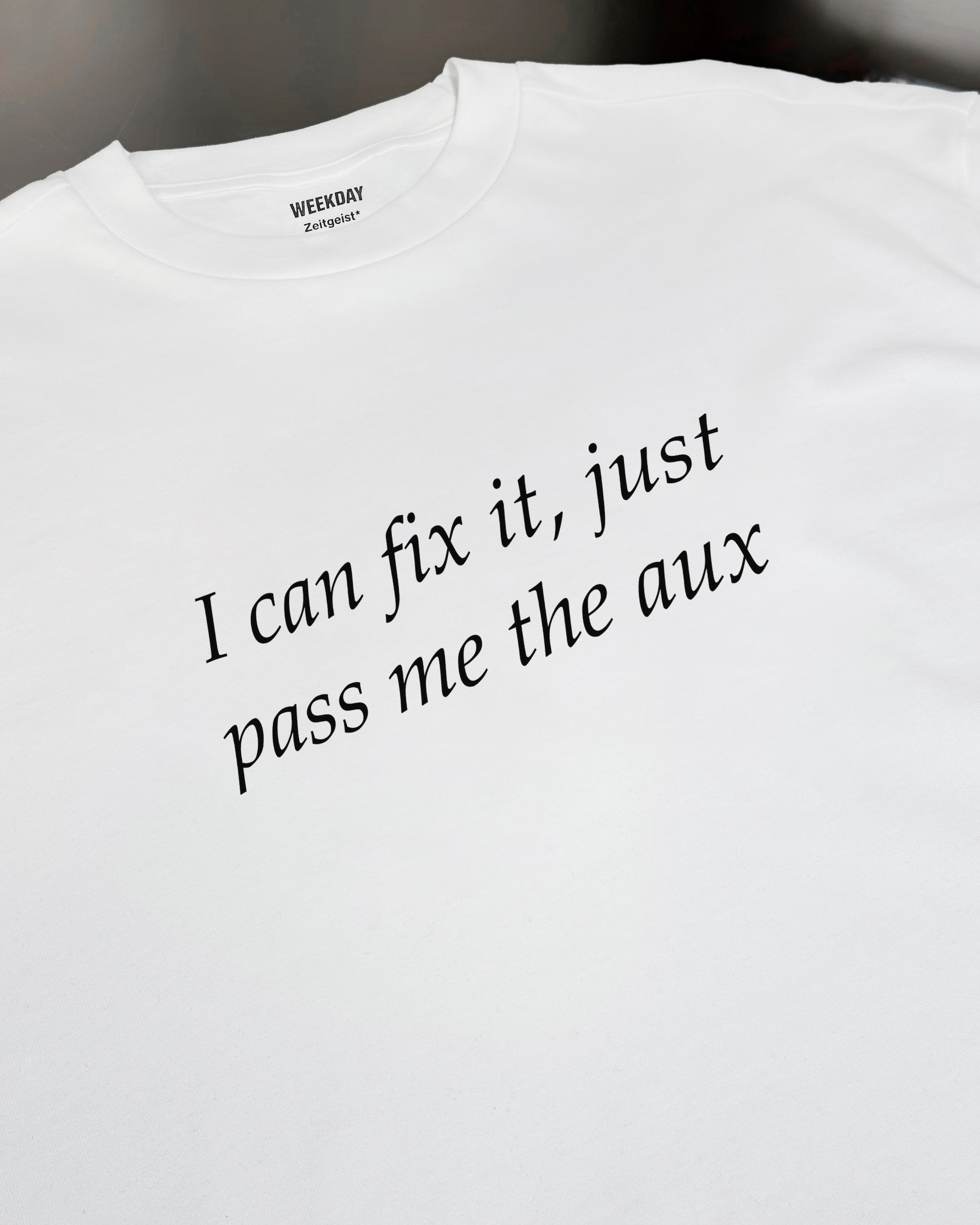 A person wearing a printed white Zeitgeist t-shirt saying “Sorry I missed your call. I was watching it ring till it stopped.”