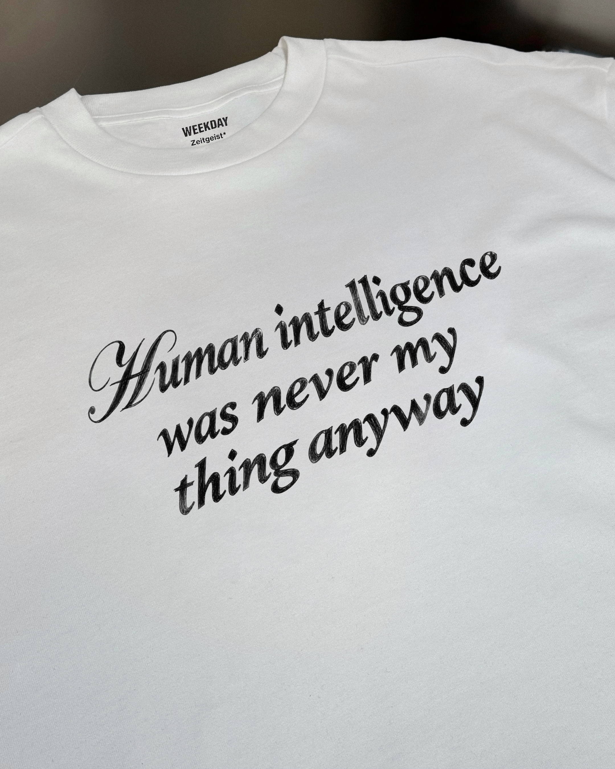 A person wearing a printed white Zeitgeist t-shirt saying “Sorry I missed your call. I was watching it ring till it stopped.”