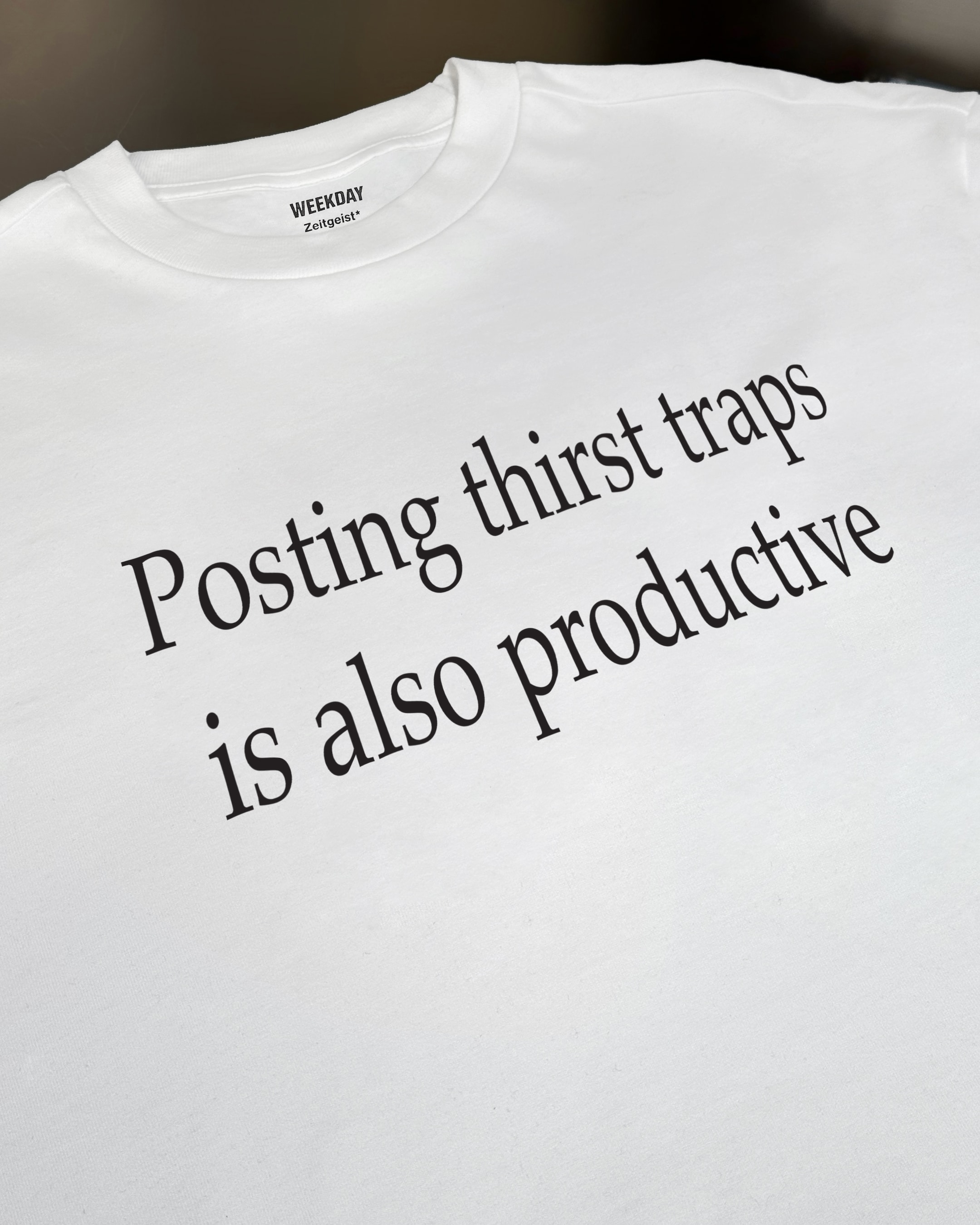 A person wearing a printed white Zeitgeist t-shirt saying “Sorry I missed your call. I was watching it ring till it stopped.”