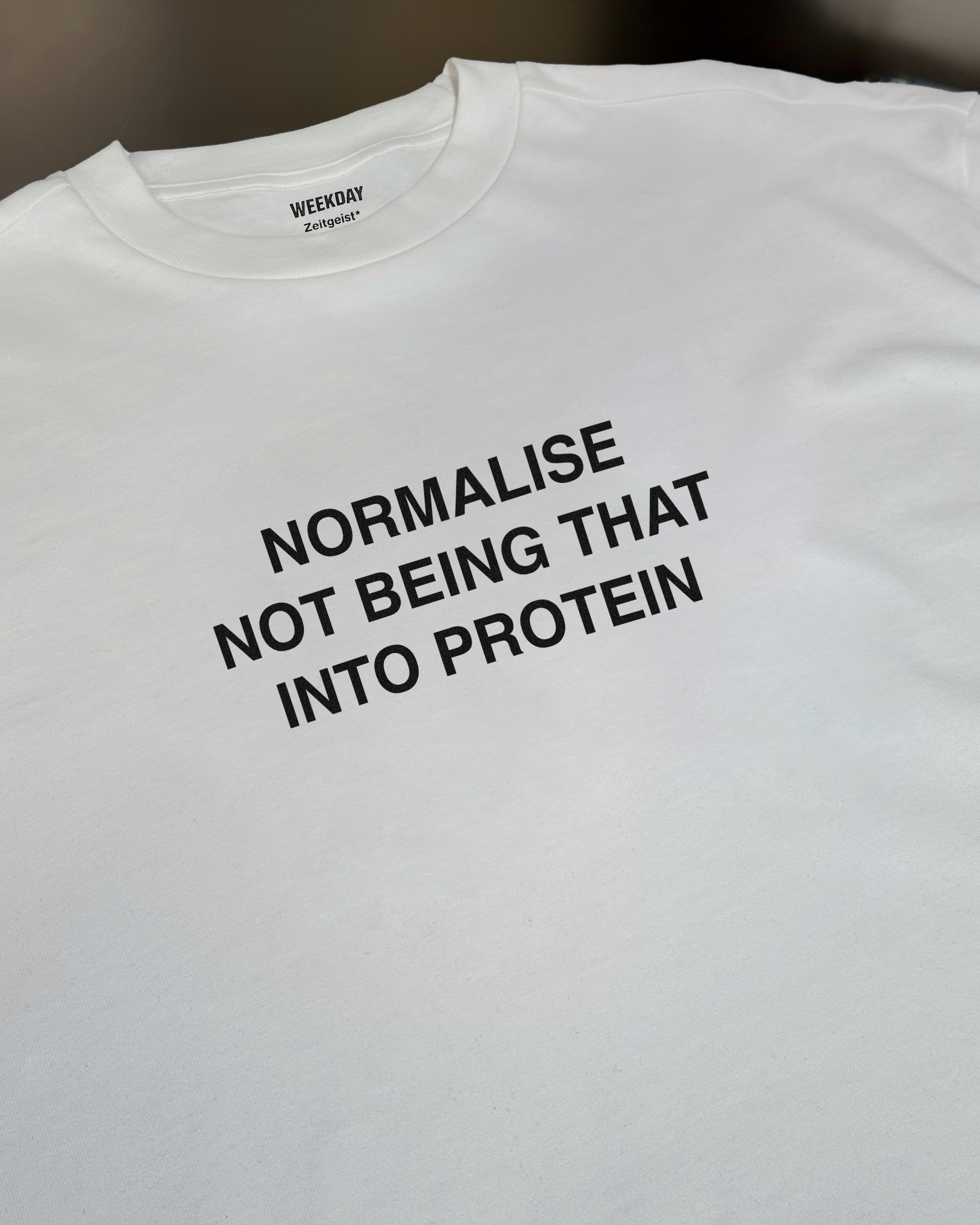 A person wearing a printed white Zeitgeist t-shirt saying “Sorry I missed your call. I was watching it ring till it stopped.”