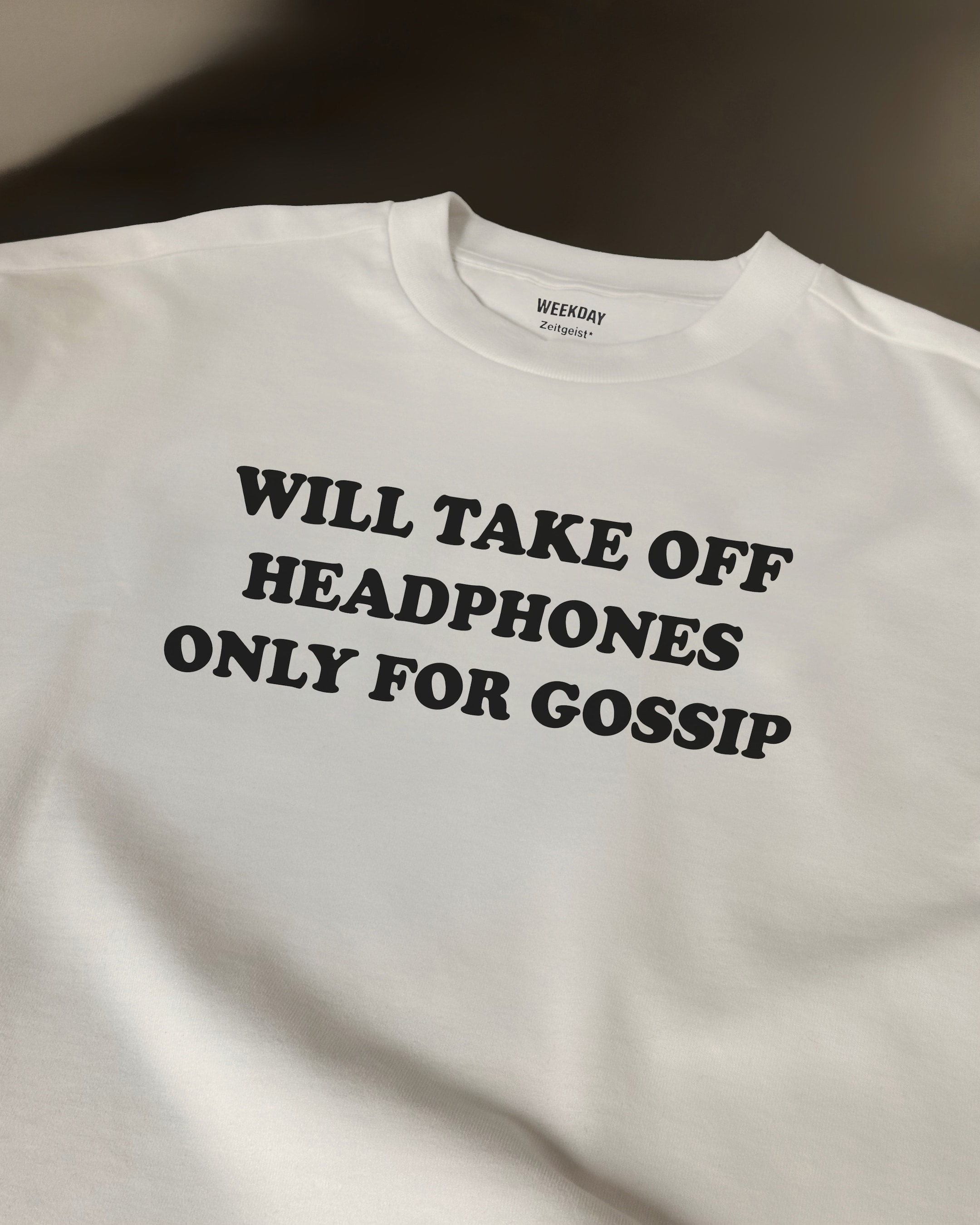 A person wearing a printed white Zeitgeist t-shirt saying “Sorry I missed your call. I was watching it ring till it stopped.”