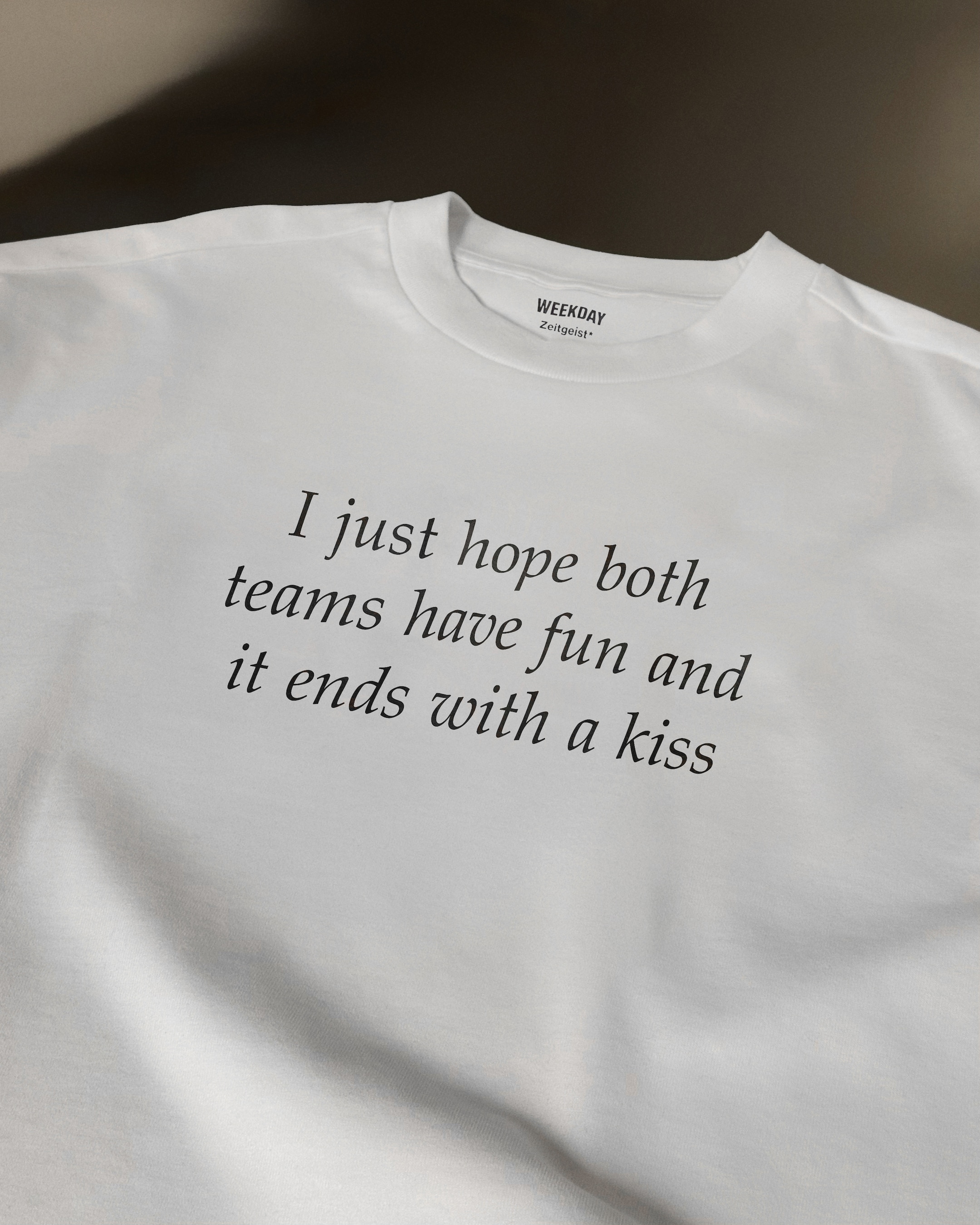 A person wearing a printed white Zeitgeist t-shirt saying “Sorry I missed your call. I was watching it ring till it stopped.”