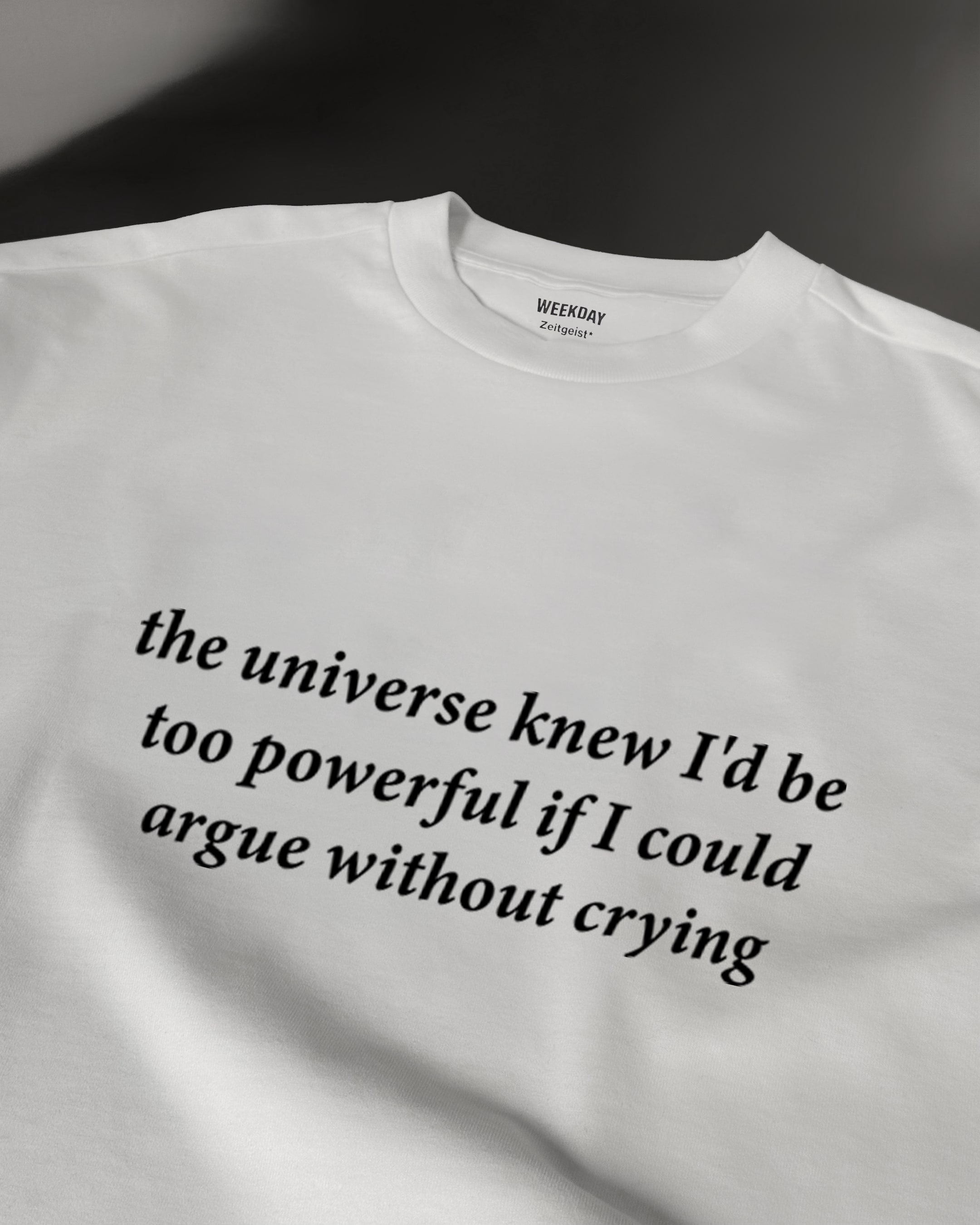 A person wearing a printed white Zeitgeist t-shirt saying “Sorry I missed your call. I was watching it ring till it stopped.”