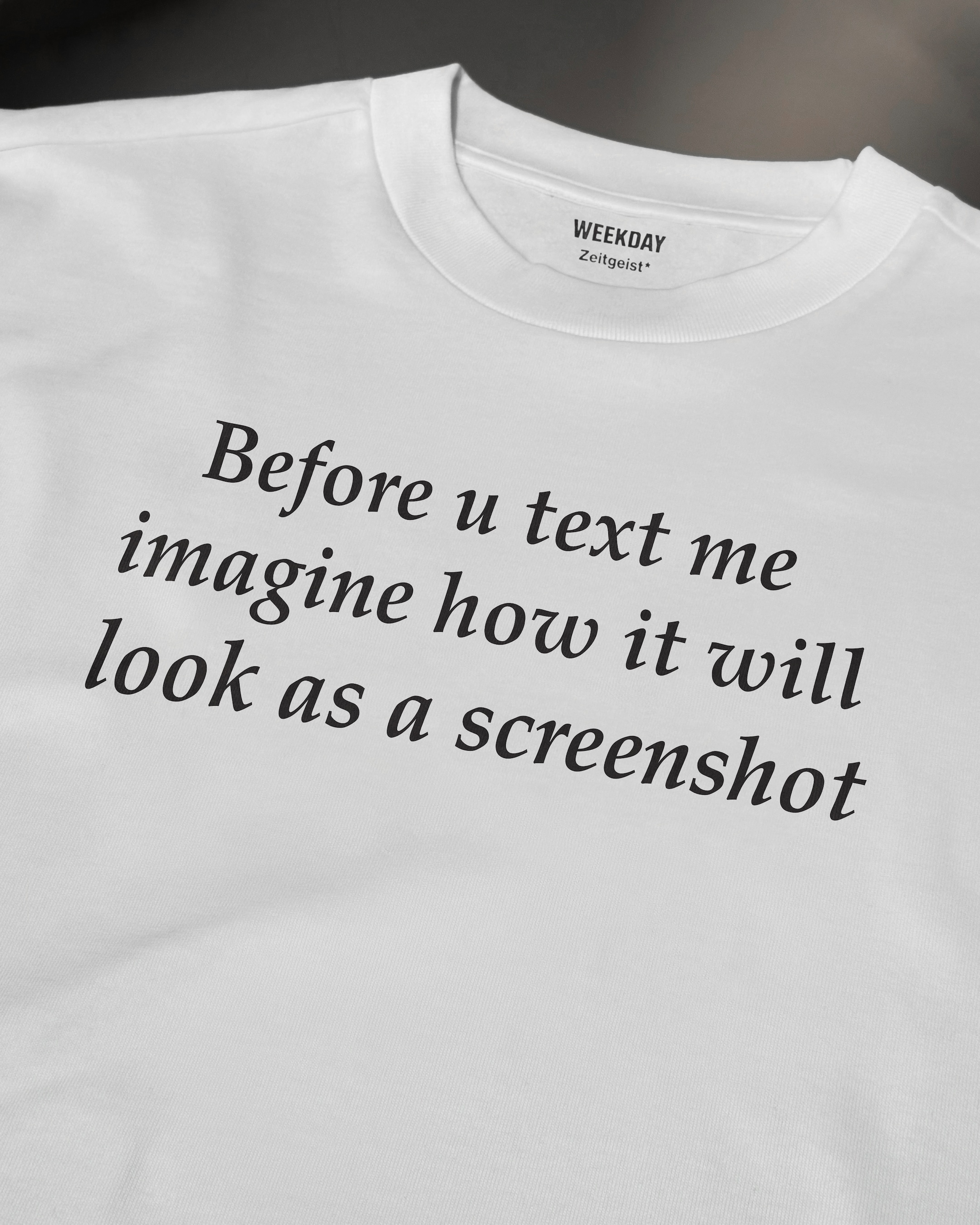 A person wearing a printed white Zeitgeist t-shirt saying “Sorry I missed your call. I was watching it ring till it stopped.”