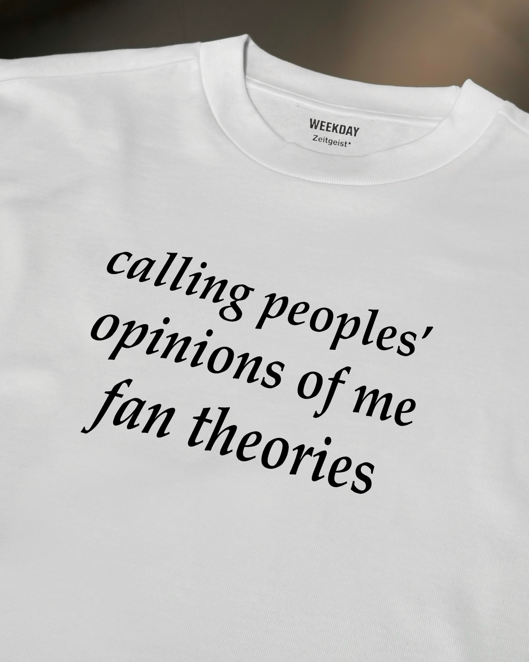 A person wearing a printed white Zeitgeist t-shirt saying “Sorry I missed your call. I was watching it ring till it stopped.”