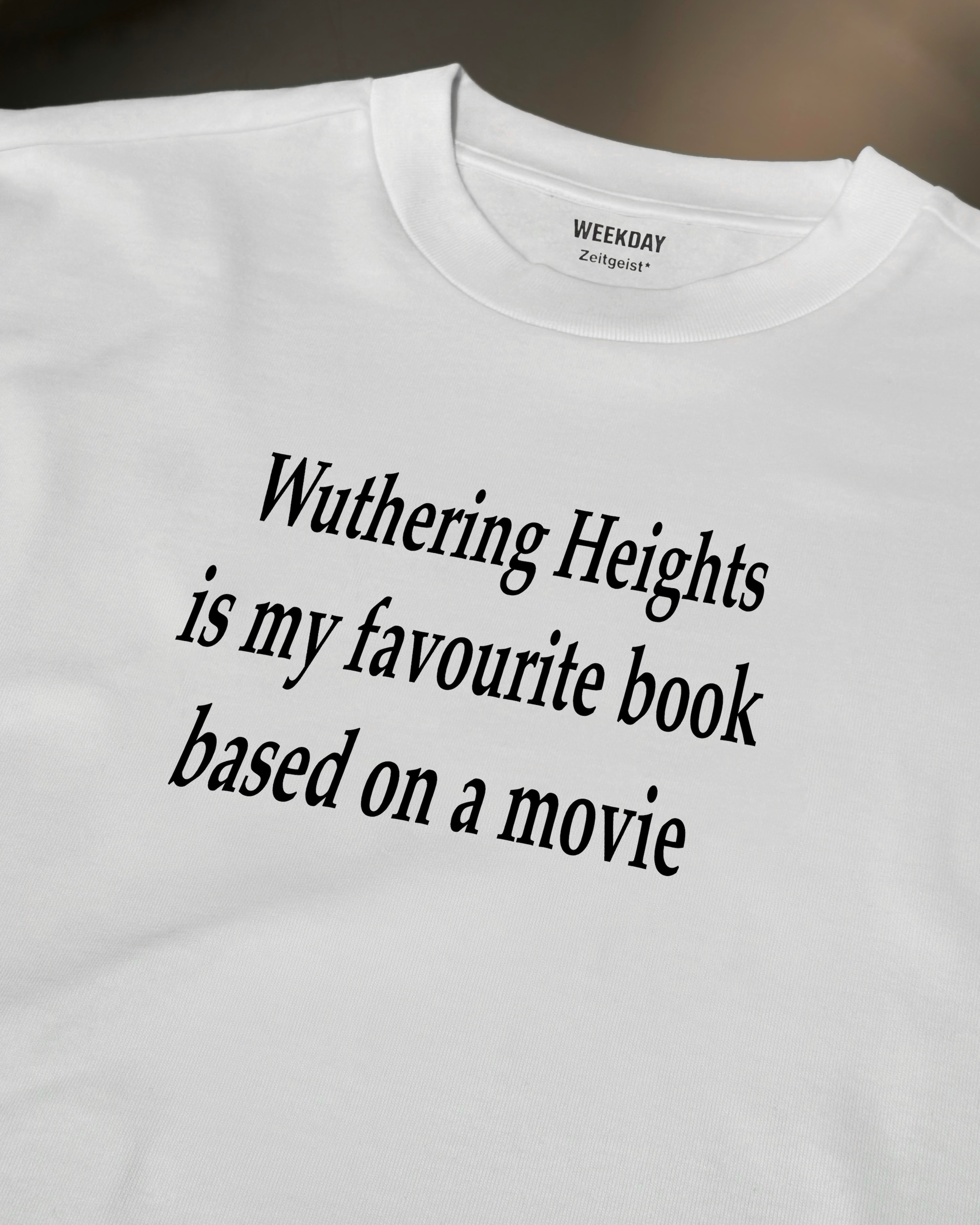 A person wearing a printed white Zeitgeist t-shirt saying “Sorry I missed your call. I was watching it ring till it stopped.”
