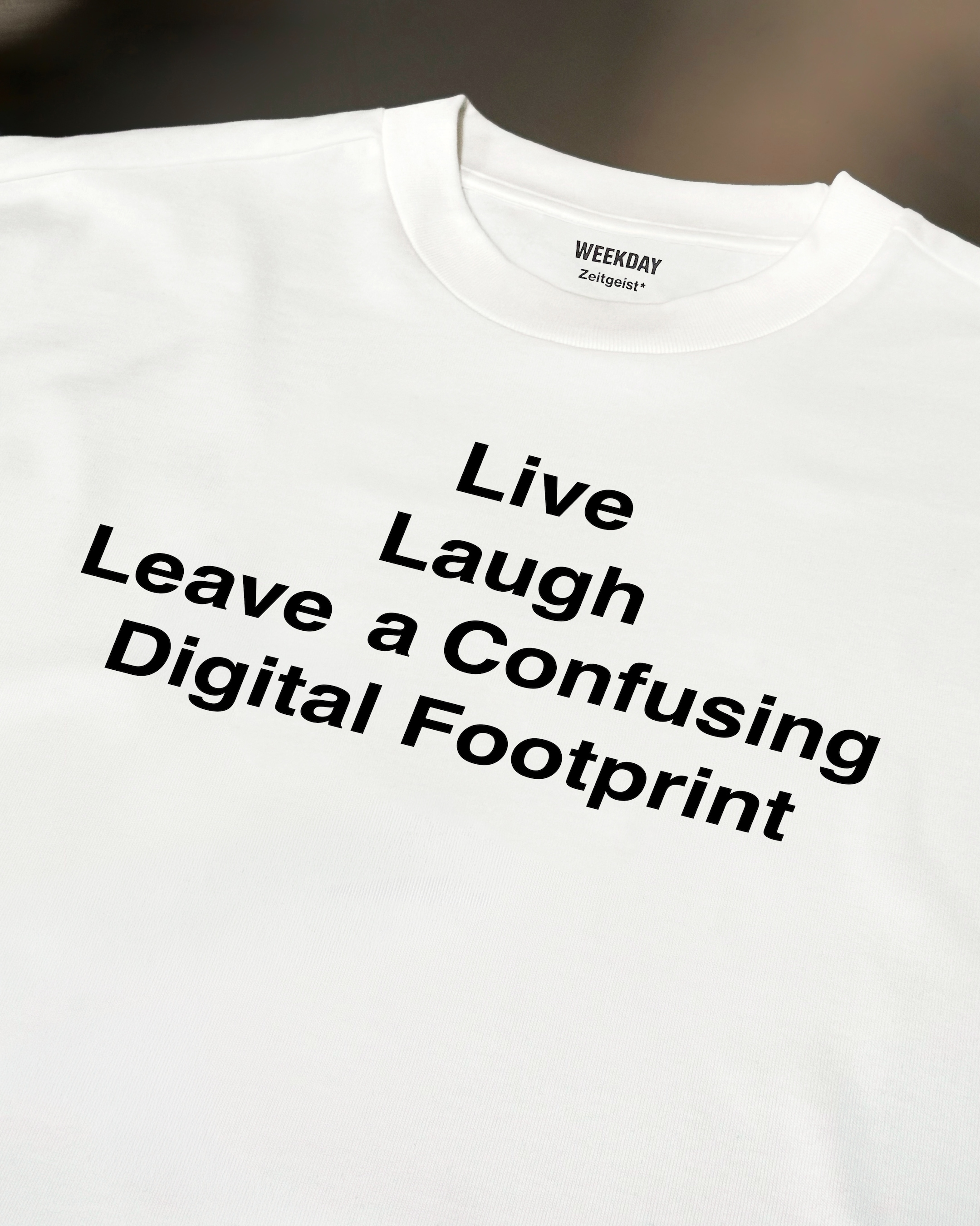 A person wearing a printed white Zeitgeist t-shirt saying “Sorry I missed your call. I was watching it ring till it stopped.”