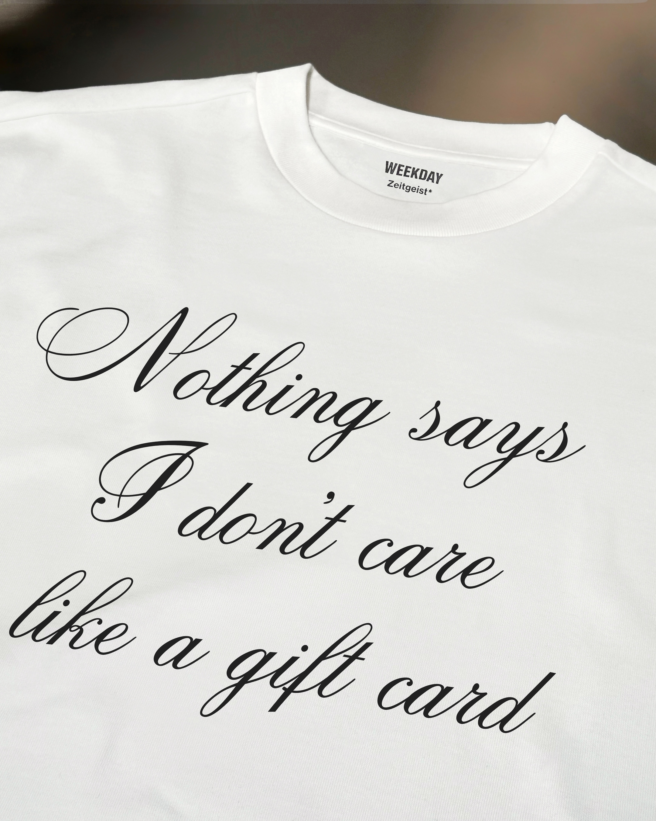 A person wearing a printed white Zeitgeist t-shirt saying “Sorry I missed your call. I was watching it ring till it stopped.”