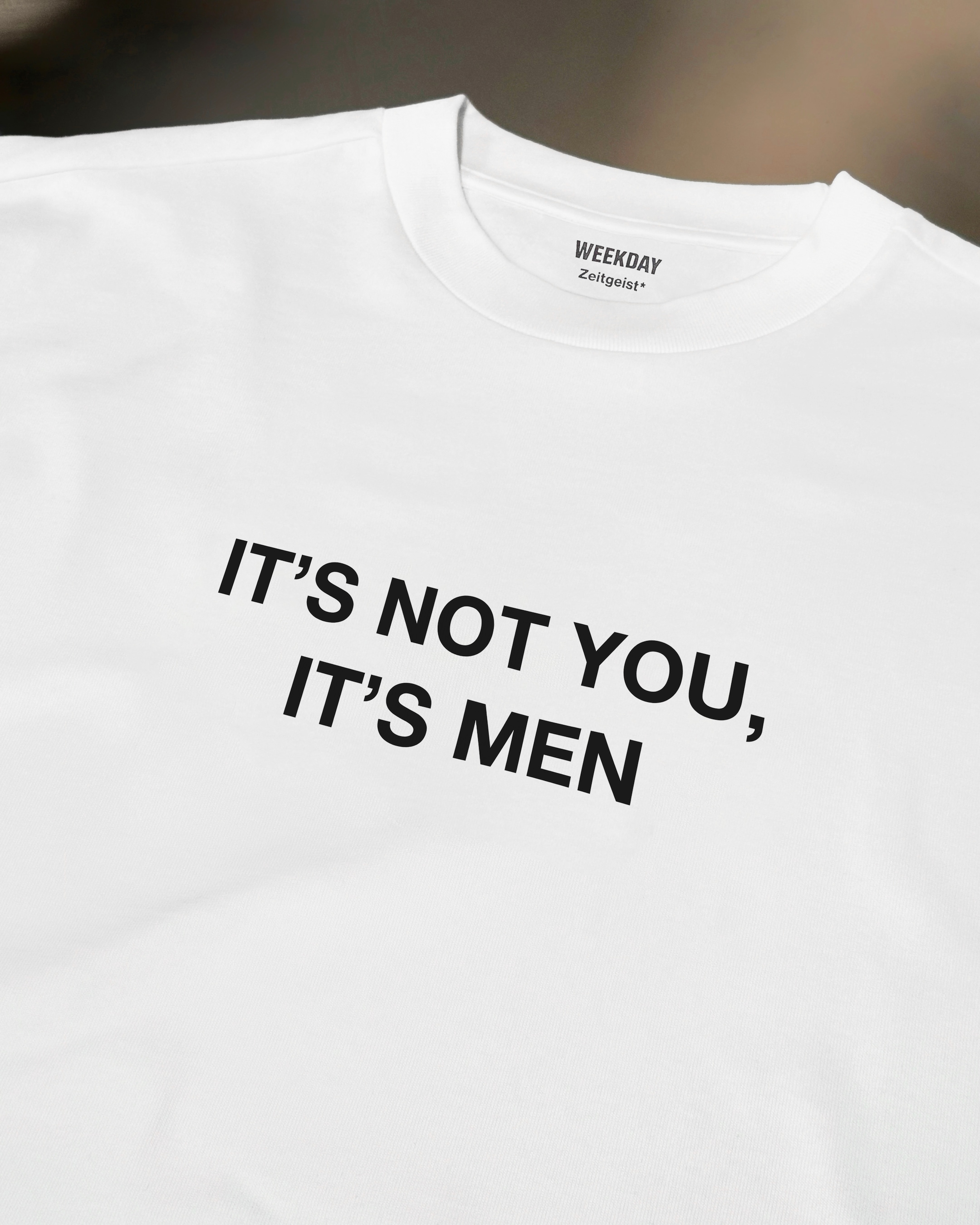 A person wearing a printed white Zeitgeist t-shirt saying “Sorry I missed your call. I was watching it ring till it stopped.”