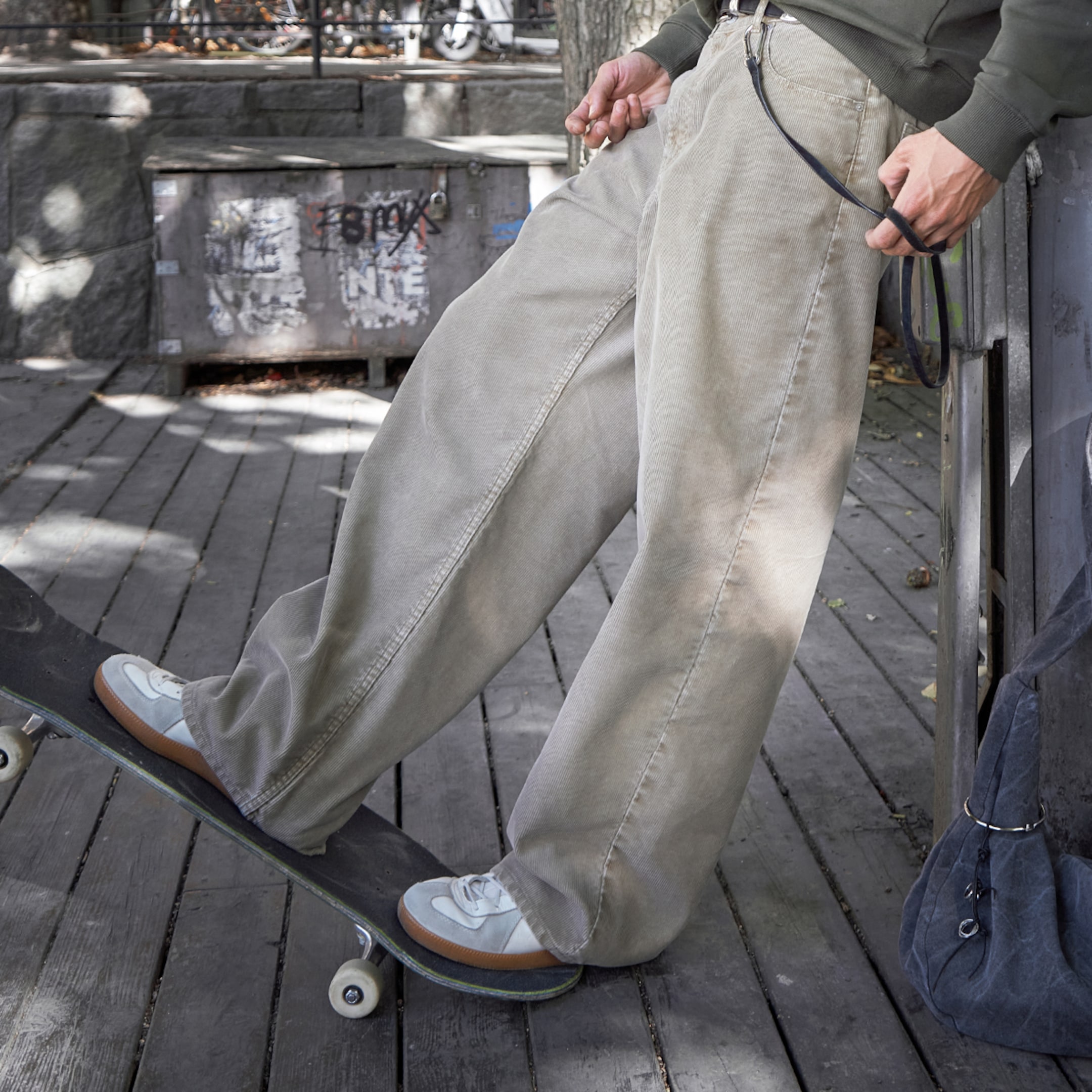 Denny Pham posing in a pair grey jeans and standing on a skateboard