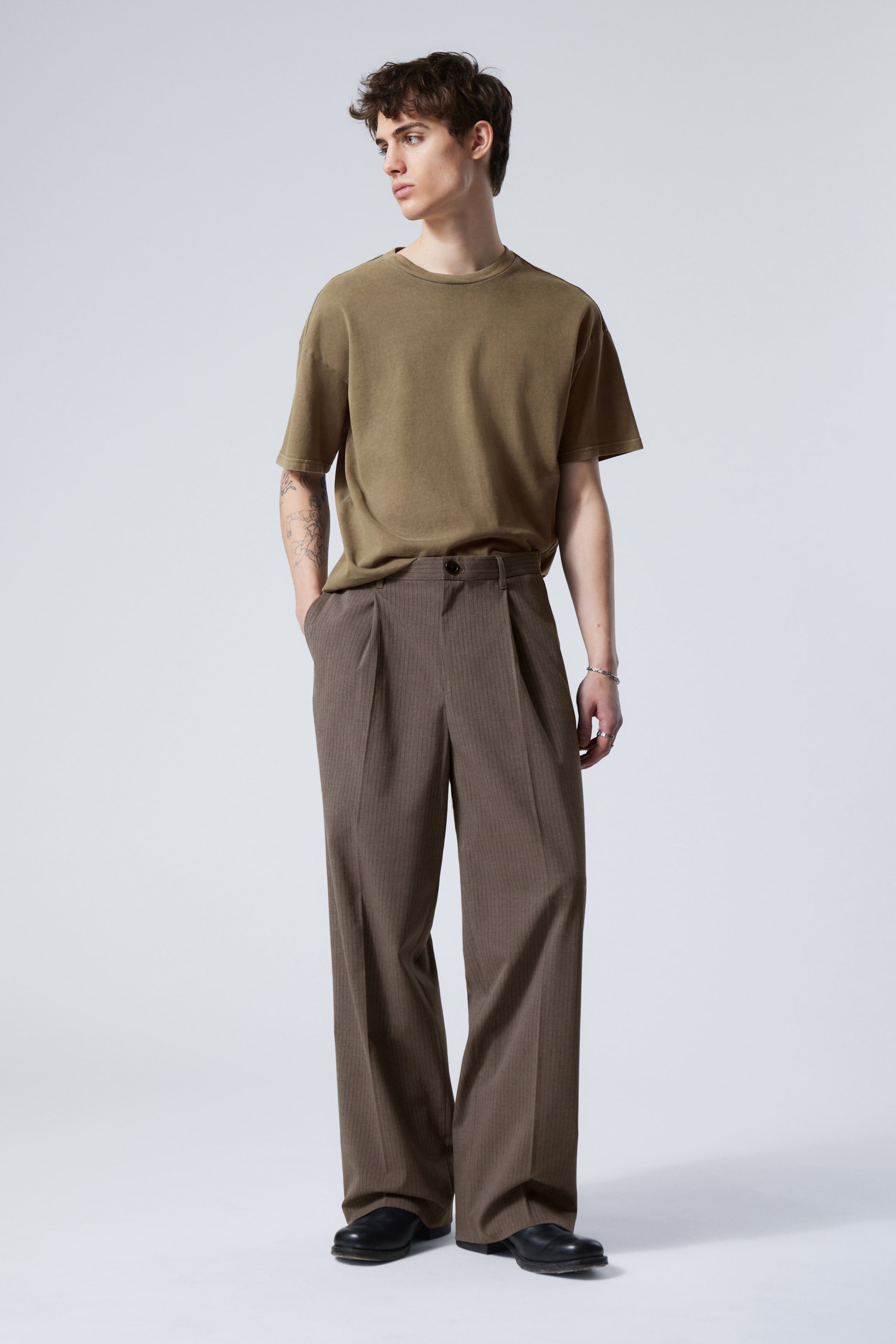 Model wearing a pair of pinstripe brown Uno trousers