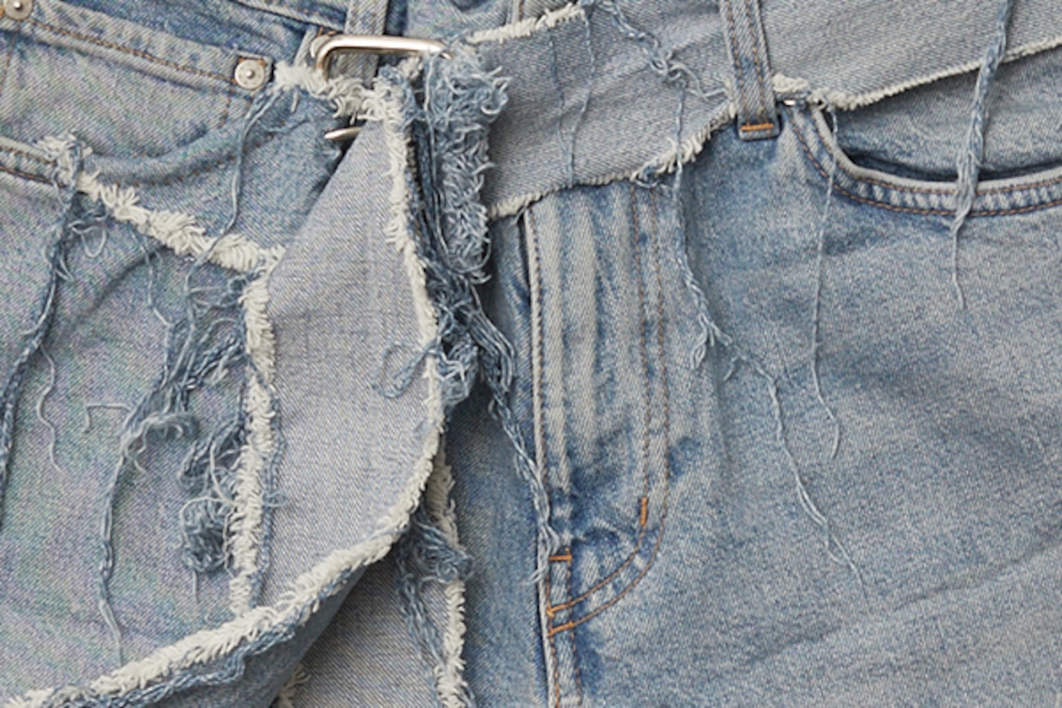 A zoomed in image of a pair of torn jeans with frayed edges.